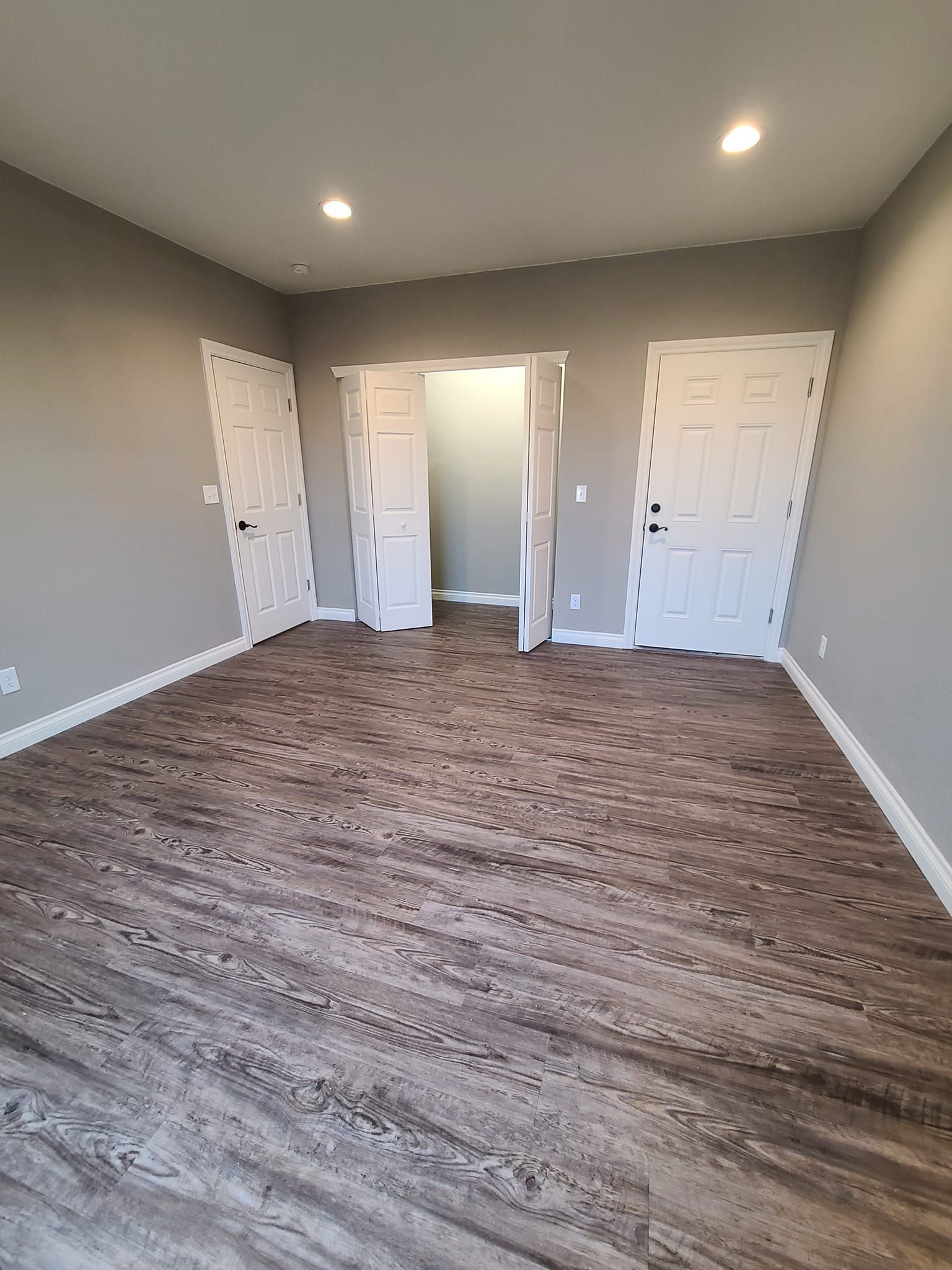 A large empty room with hardwood floors and gray walls.