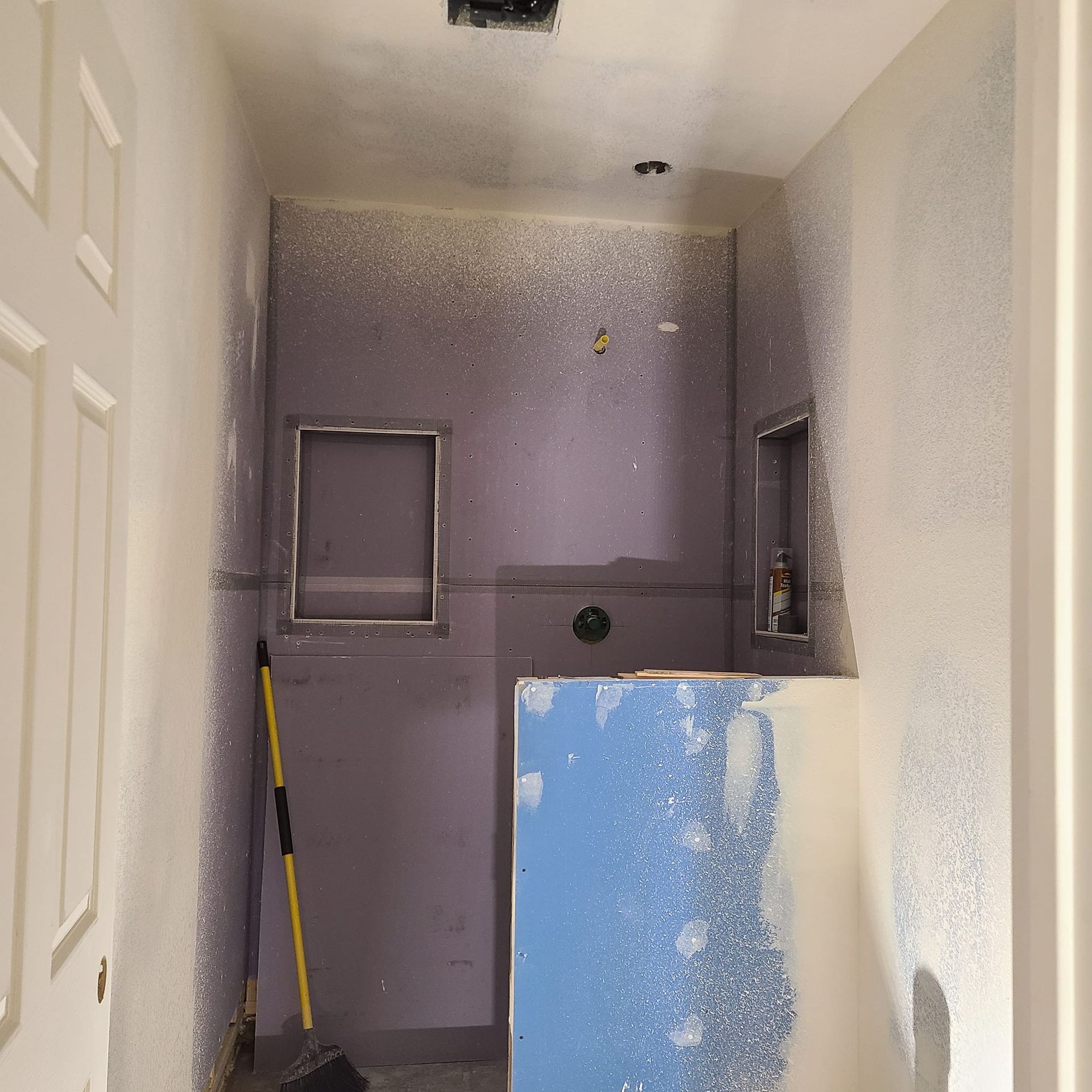 A bathroom with a purple wall and a yellow broom