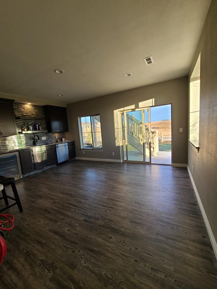 A living room with hardwood floors , a kitchen , and a sliding glass door.