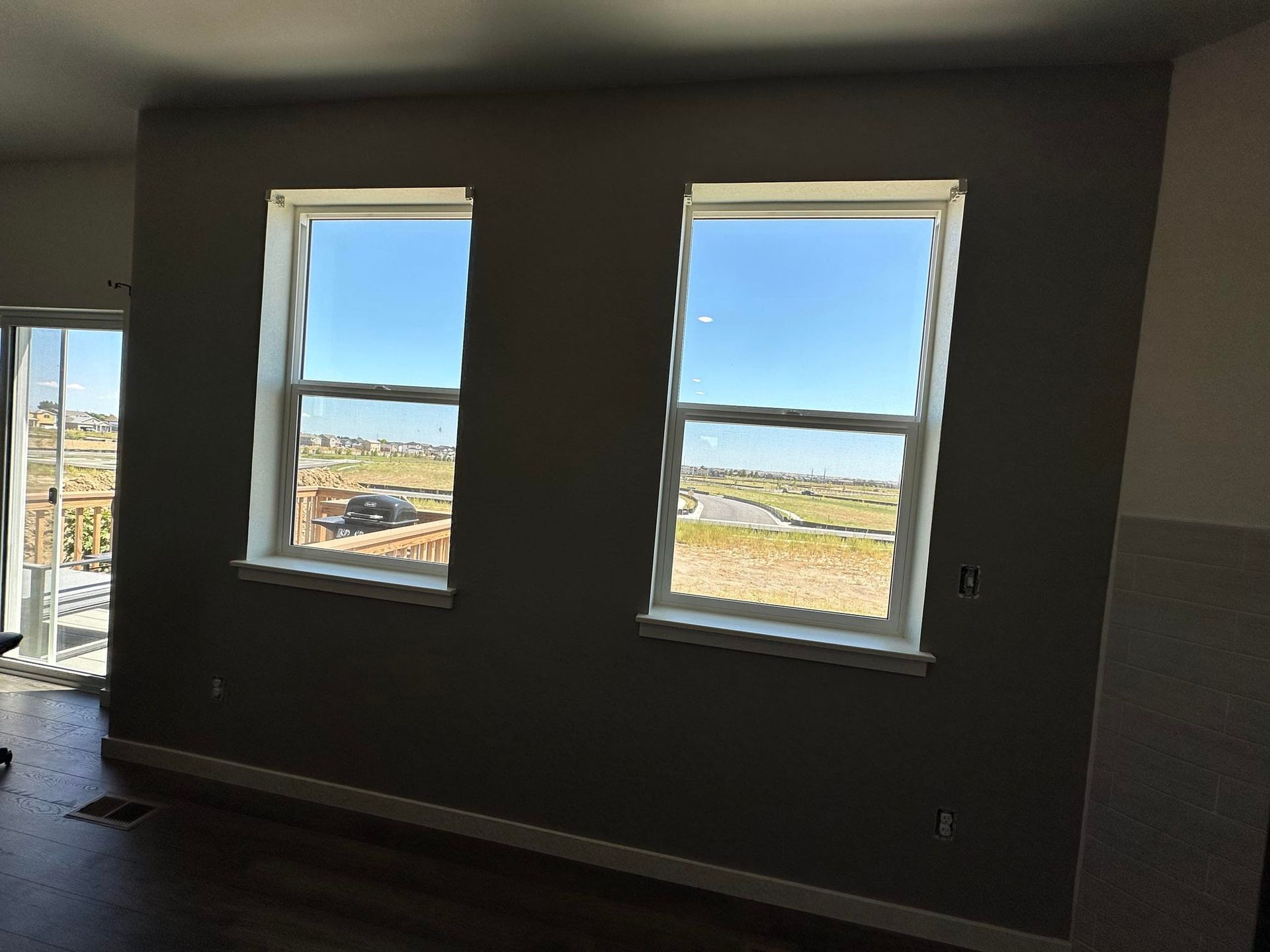 A room with two windows and a sliding glass door