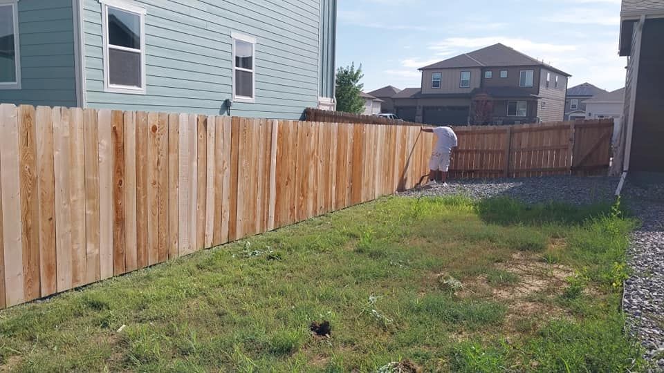 A wooden fence is being built in the backyard of a house.