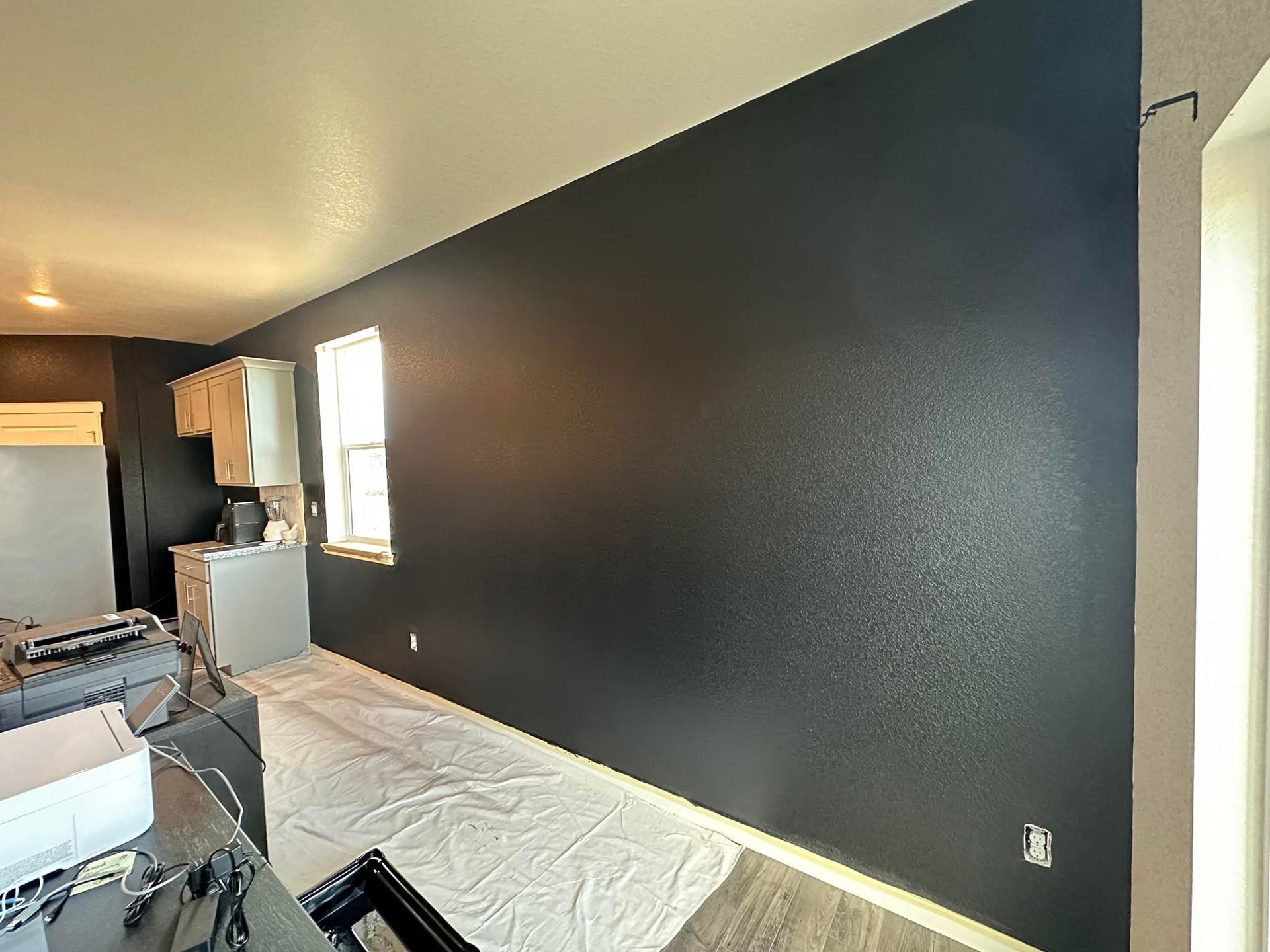 A living room with black walls and a white table cloth on the floor.