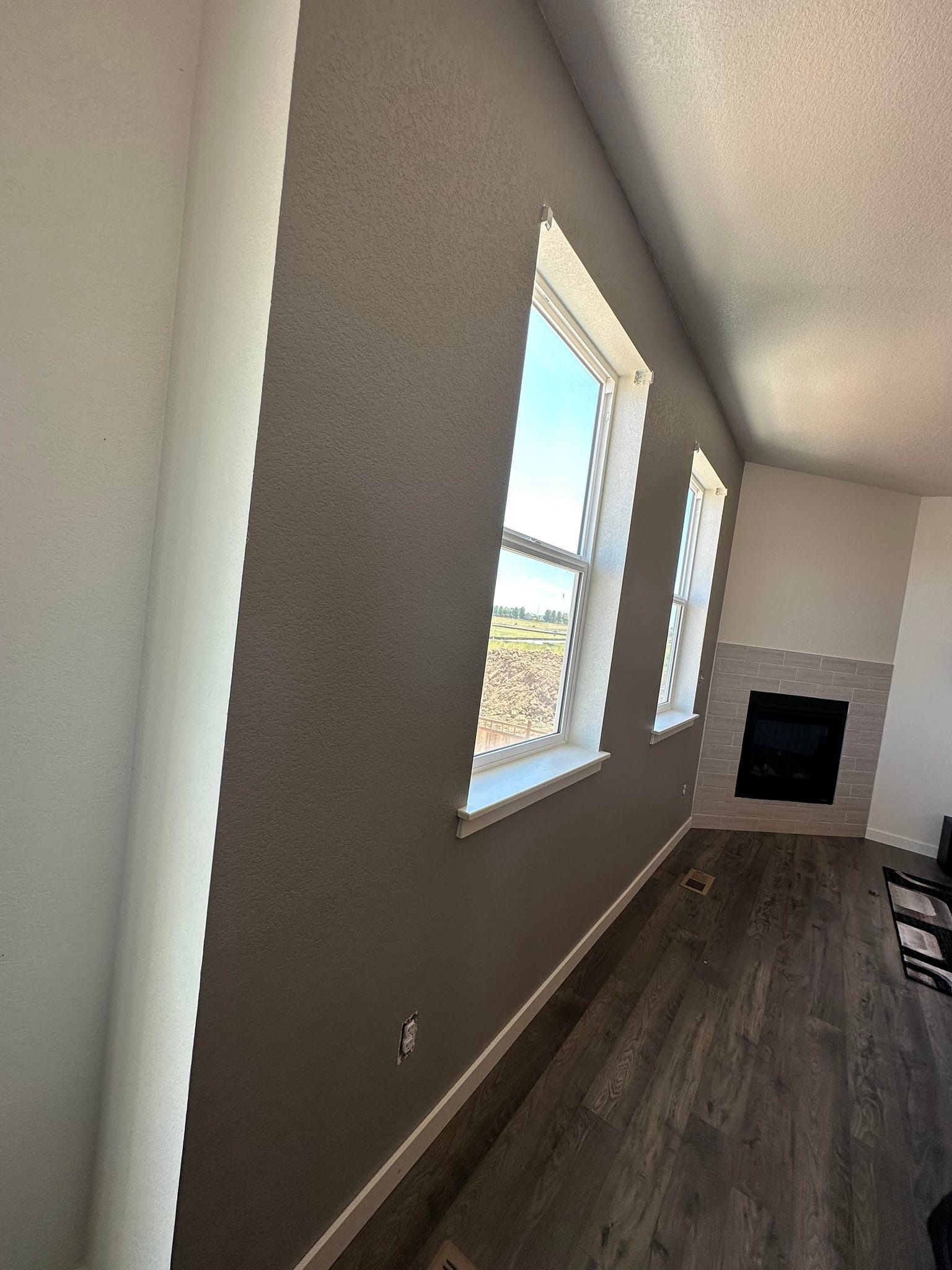 A living room with three windows and a fireplace.