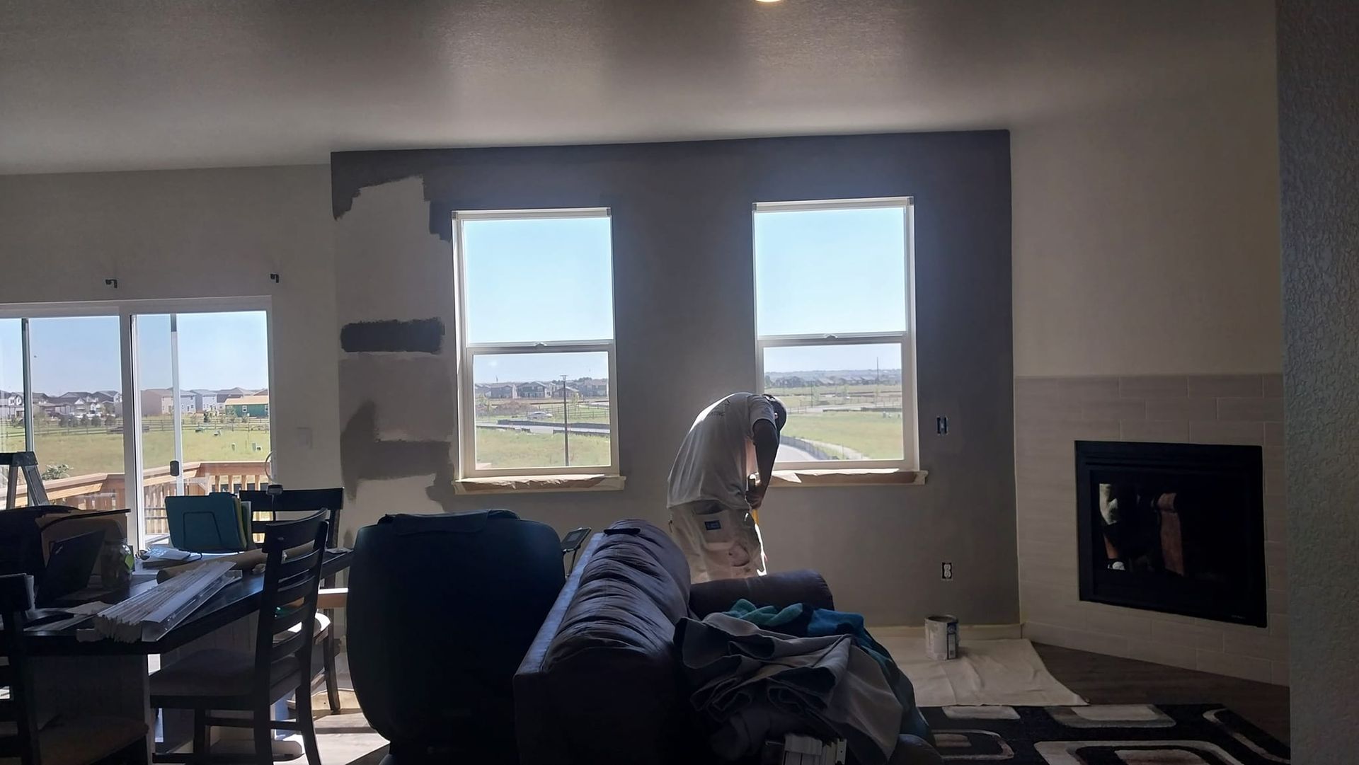 A man is painting a wall in a living room.