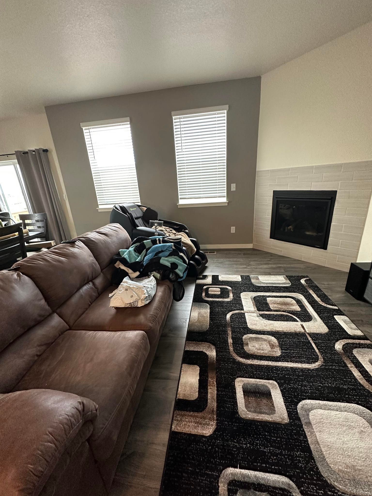 A living room with a couch , chair , rug and fireplace.
