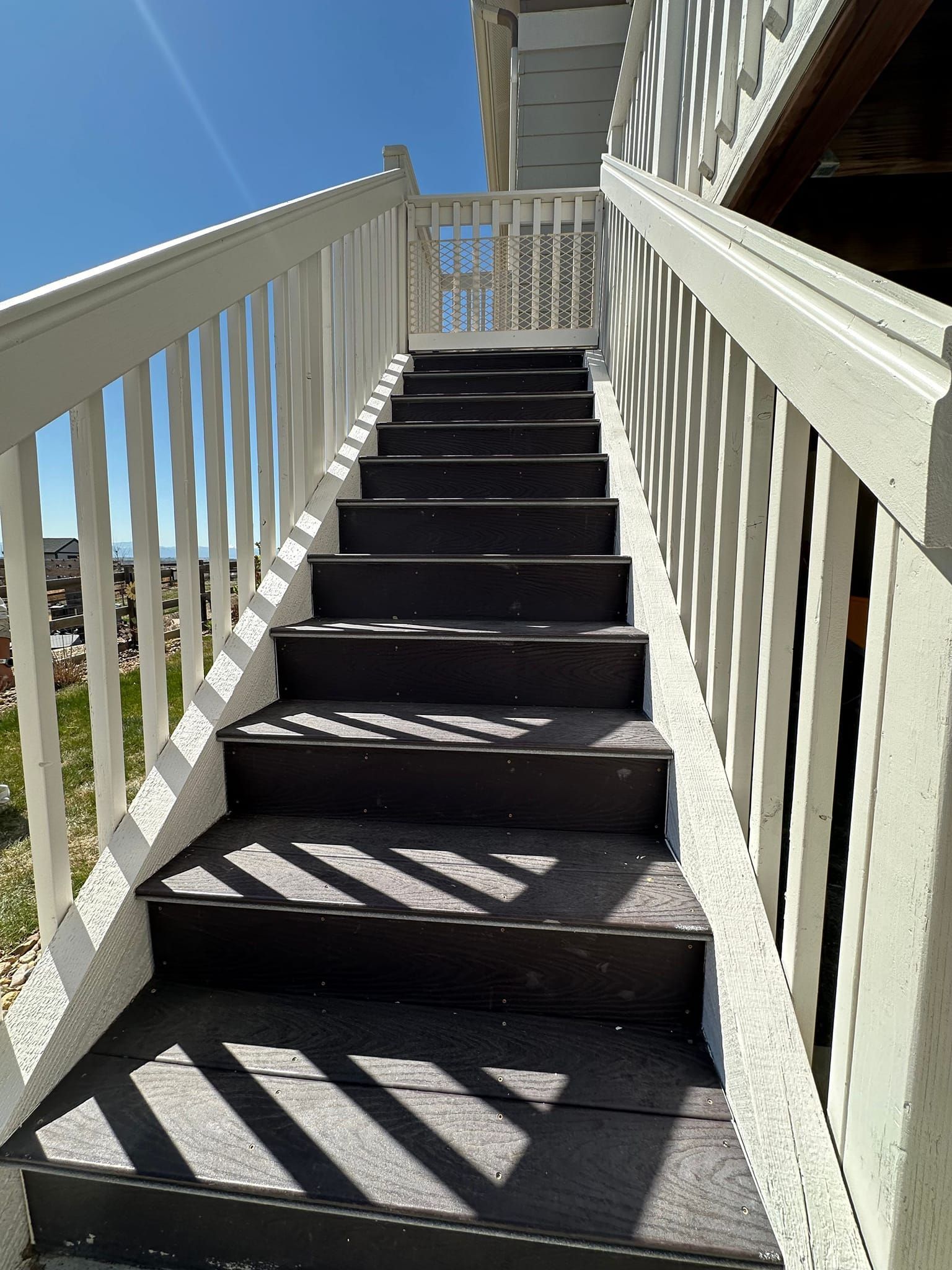 A set of stairs leading up to a deck with a white railing.