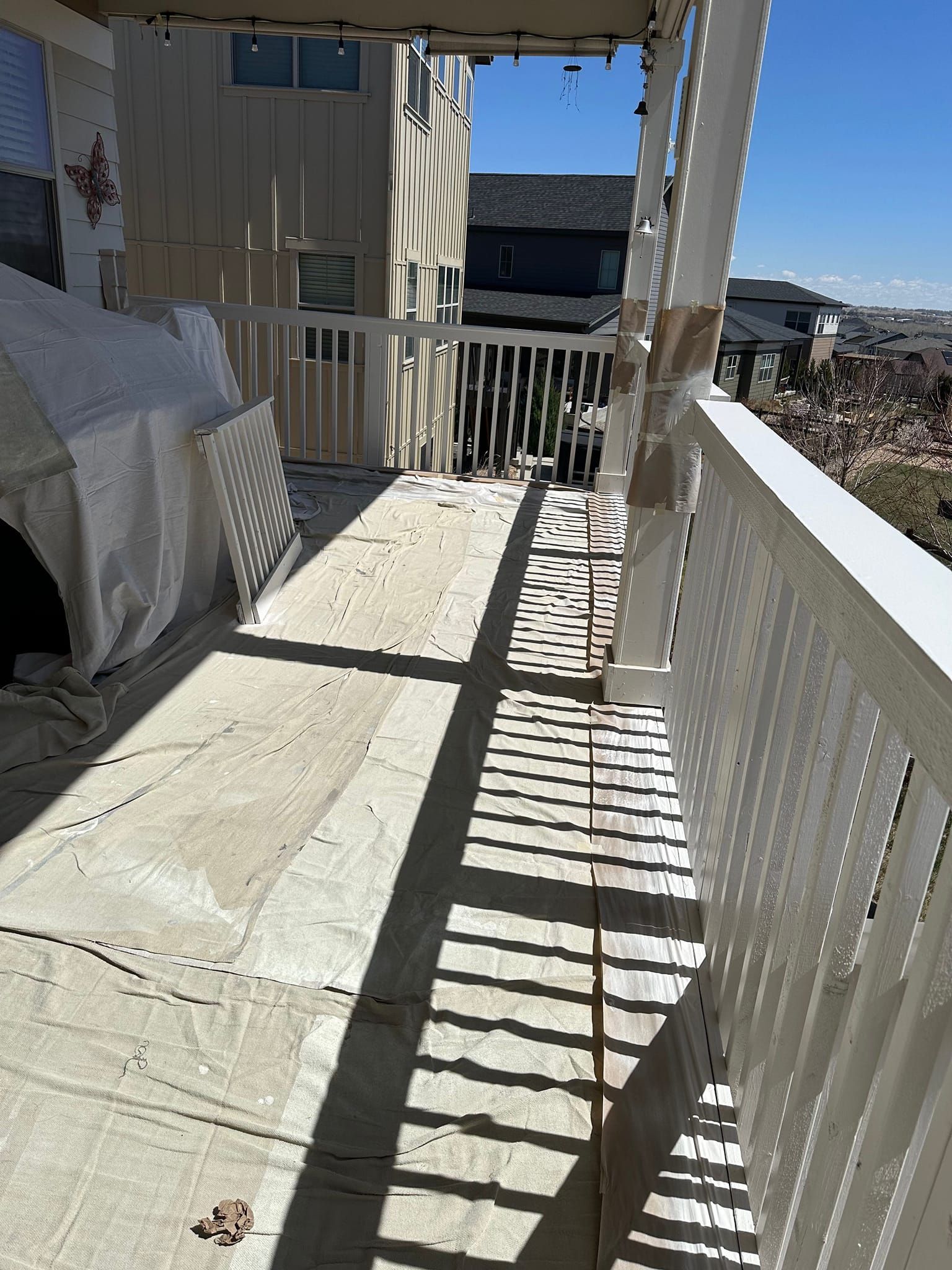 A balcony with a white railing and a building in the background.