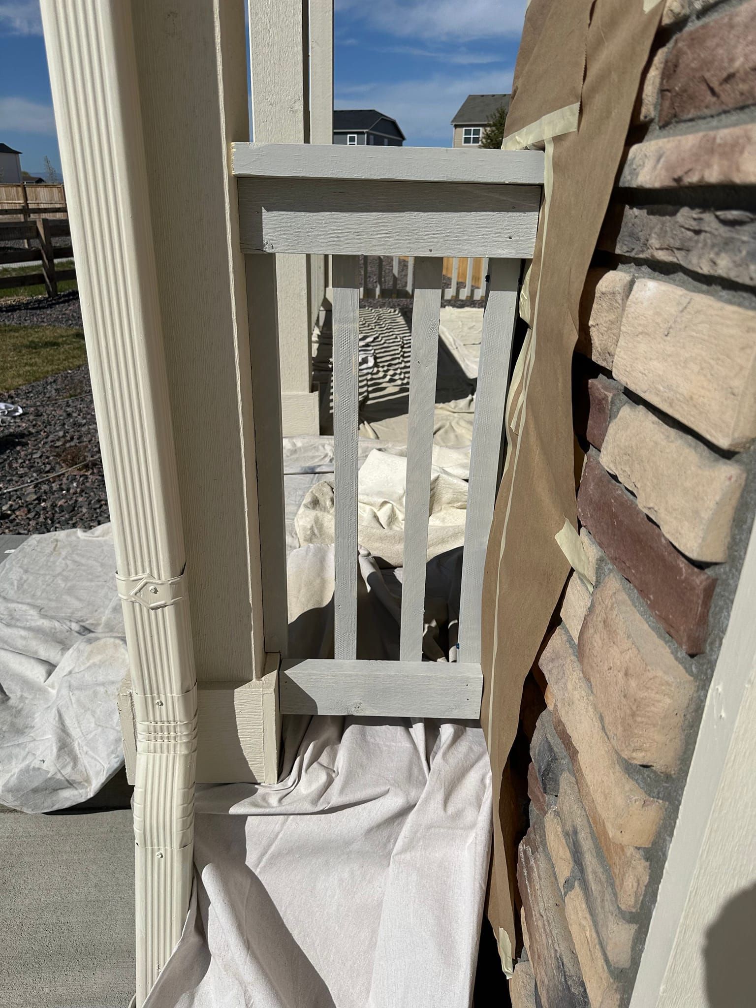 A white fence is sitting next to a brick wall.