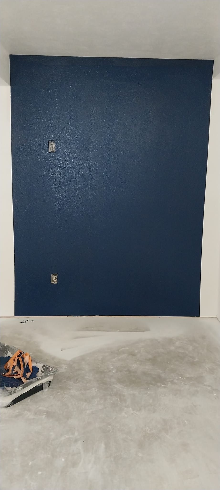 A blue wall is being painted in a room.