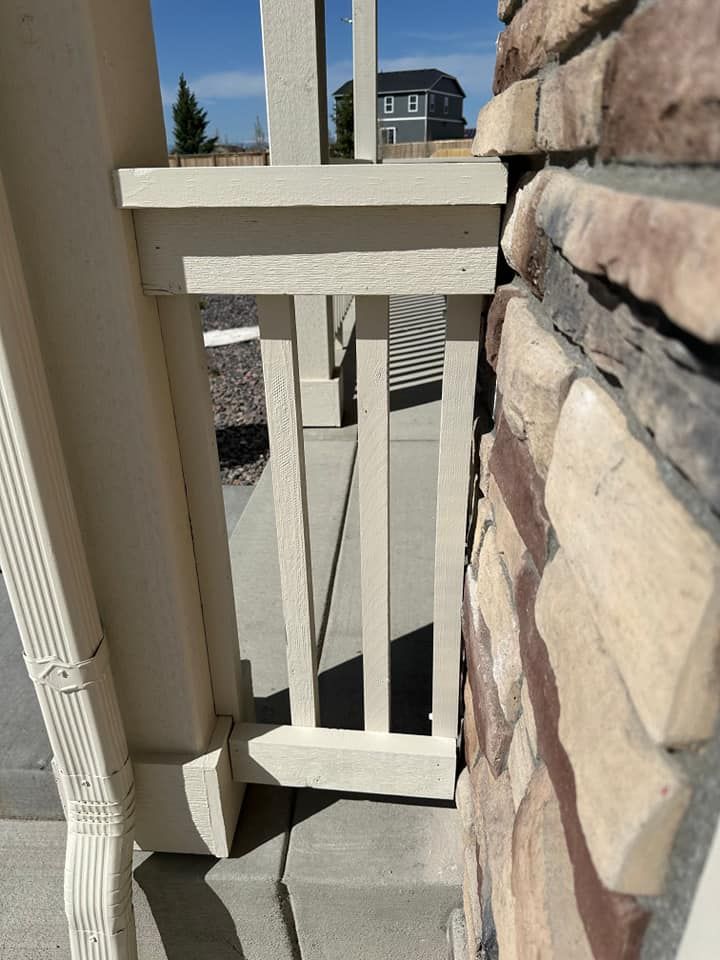 A white railing is sitting next to a stone wall.