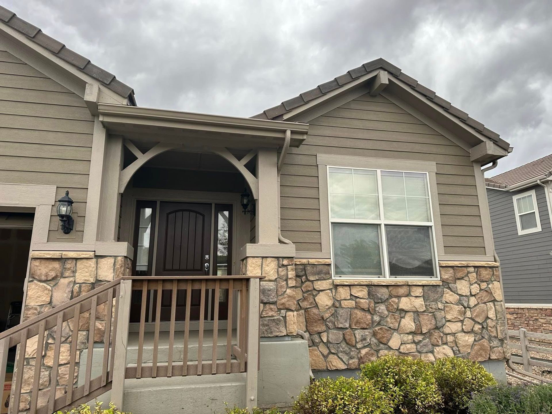 The front of a house with a stone wall and a porch.
