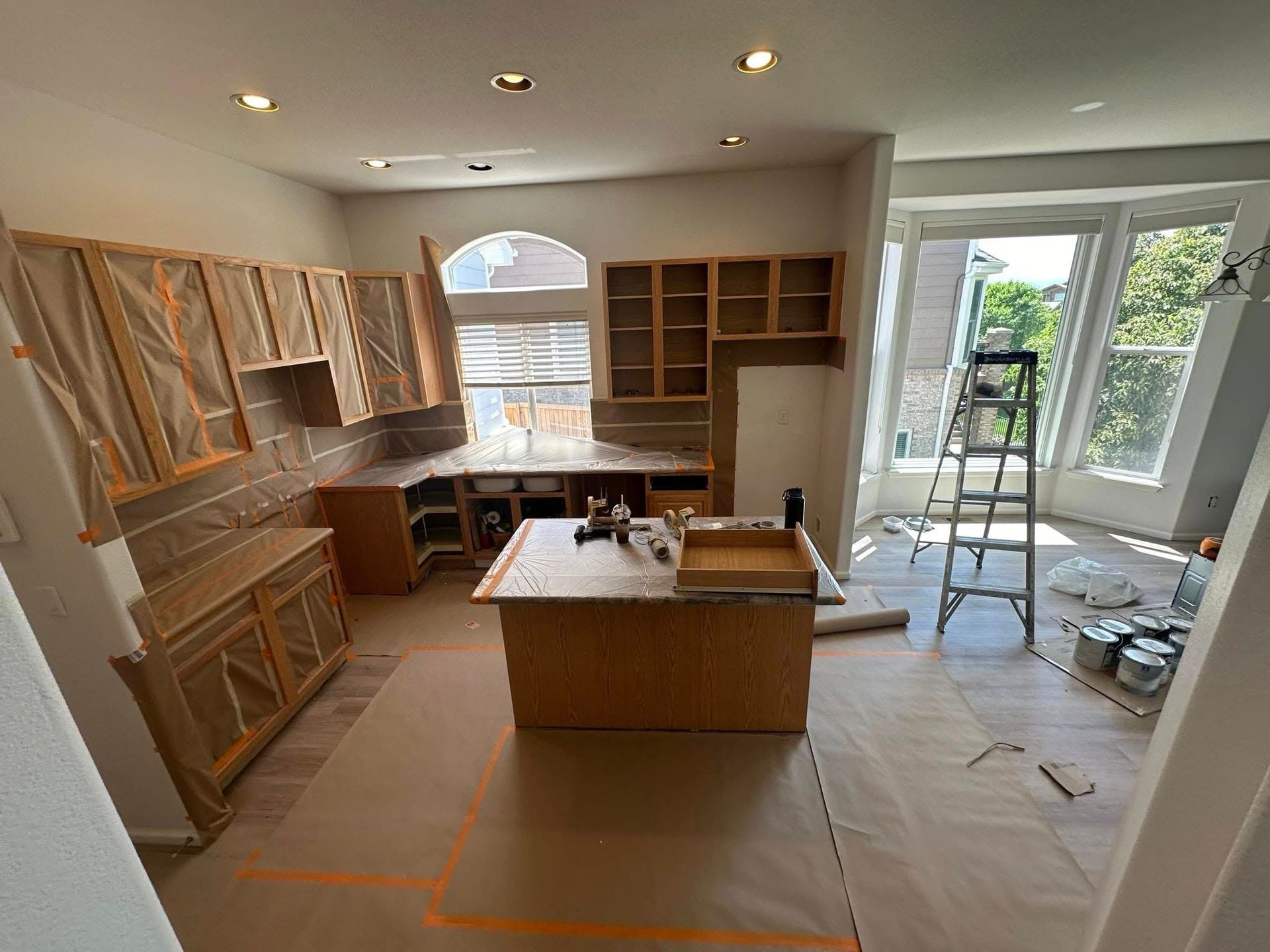A kitchen is being remodeled with wooden cabinets and a large island.