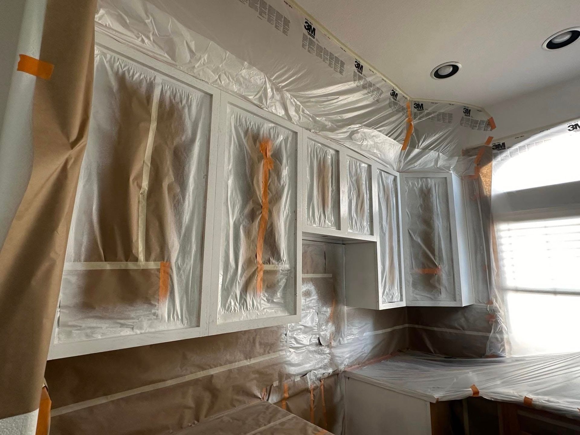 A kitchen with cabinets covered in plastic and tape.