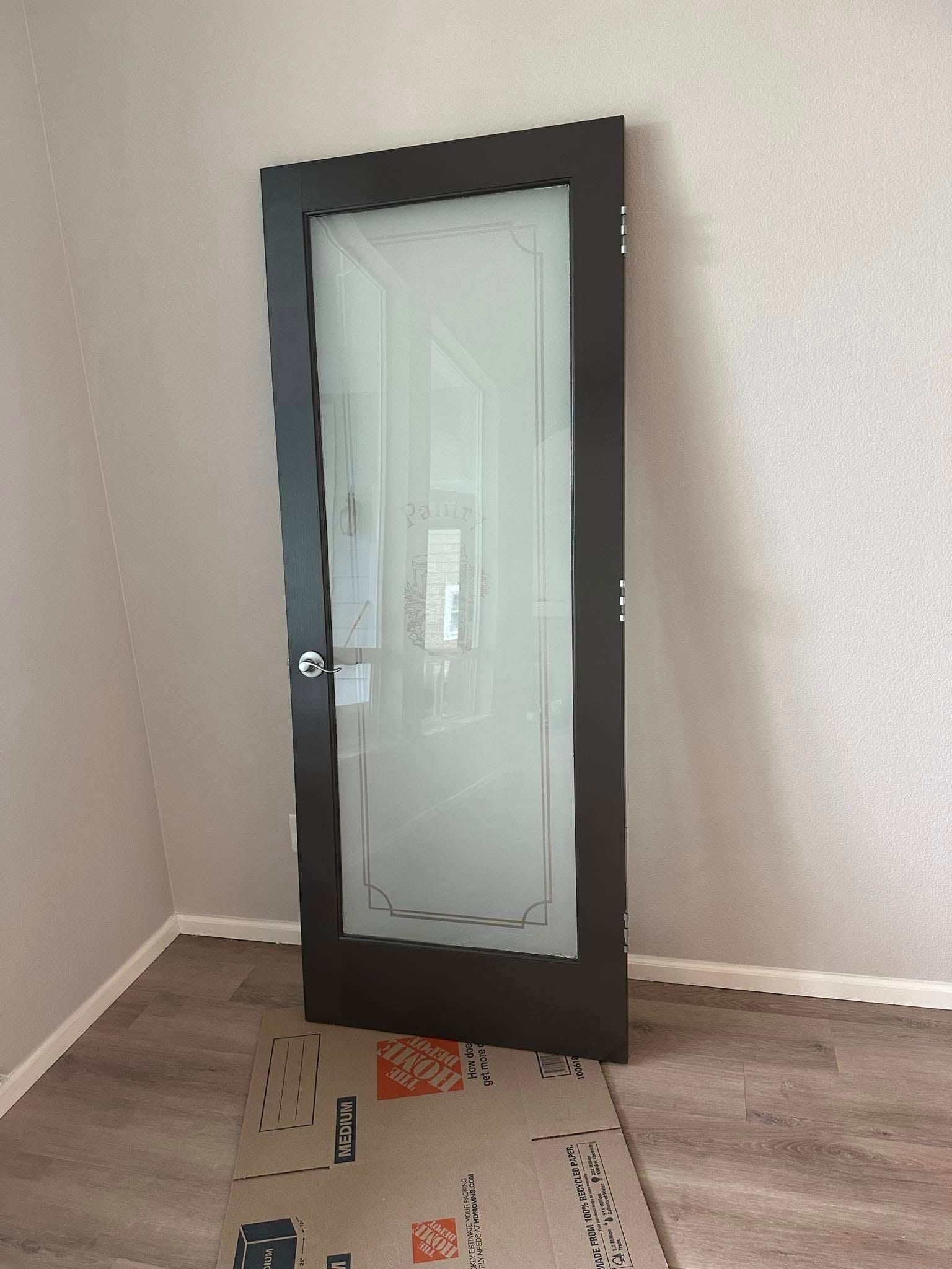 A black door with a frosted glass door in a room.