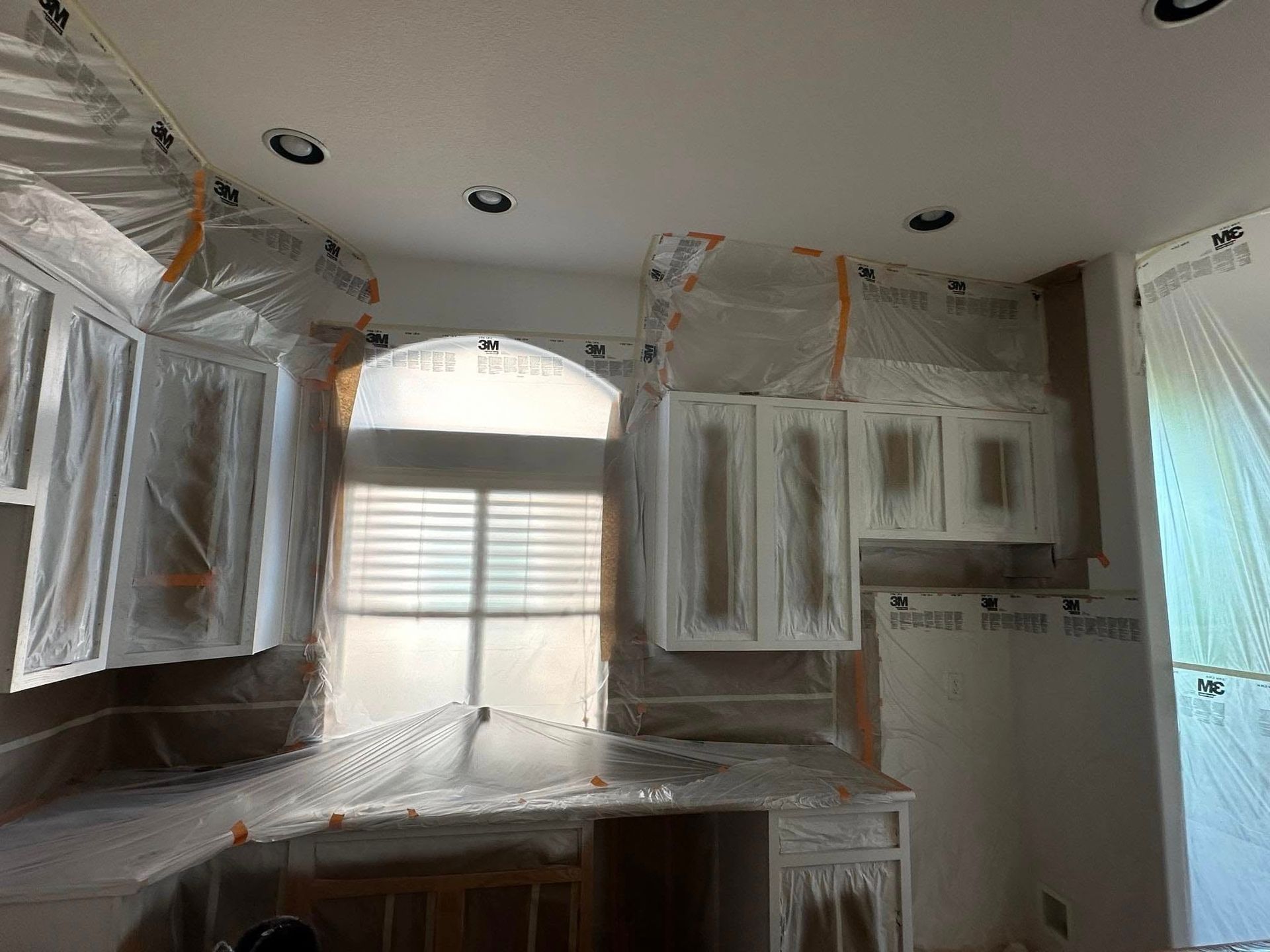 A kitchen is being painted and covered in plastic.