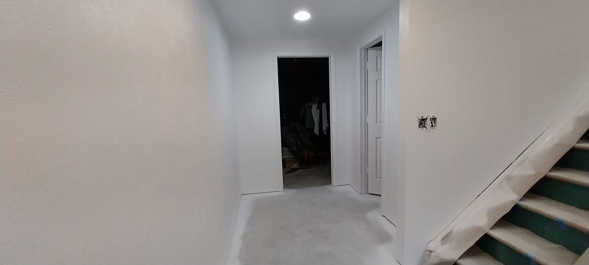 A hallway with stairs and a door in a house under construction.
