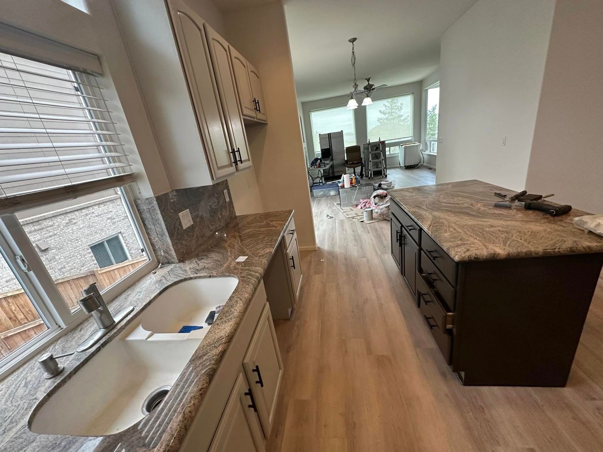 A kitchen with a sink , cabinets , and a large island.