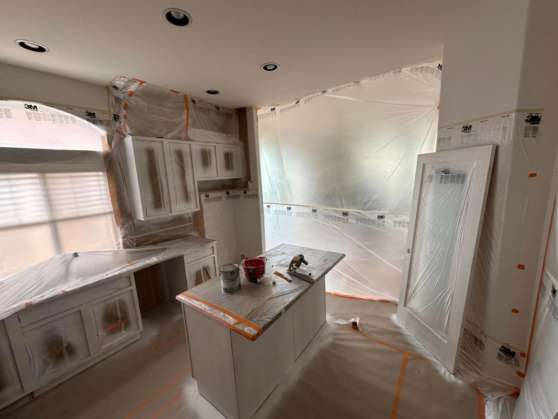 A kitchen is being painted and covered in plastic.