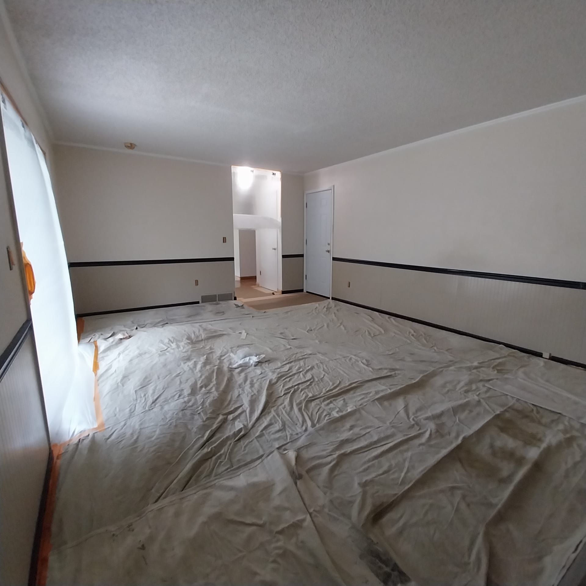 An empty room with a white tarp on the floor