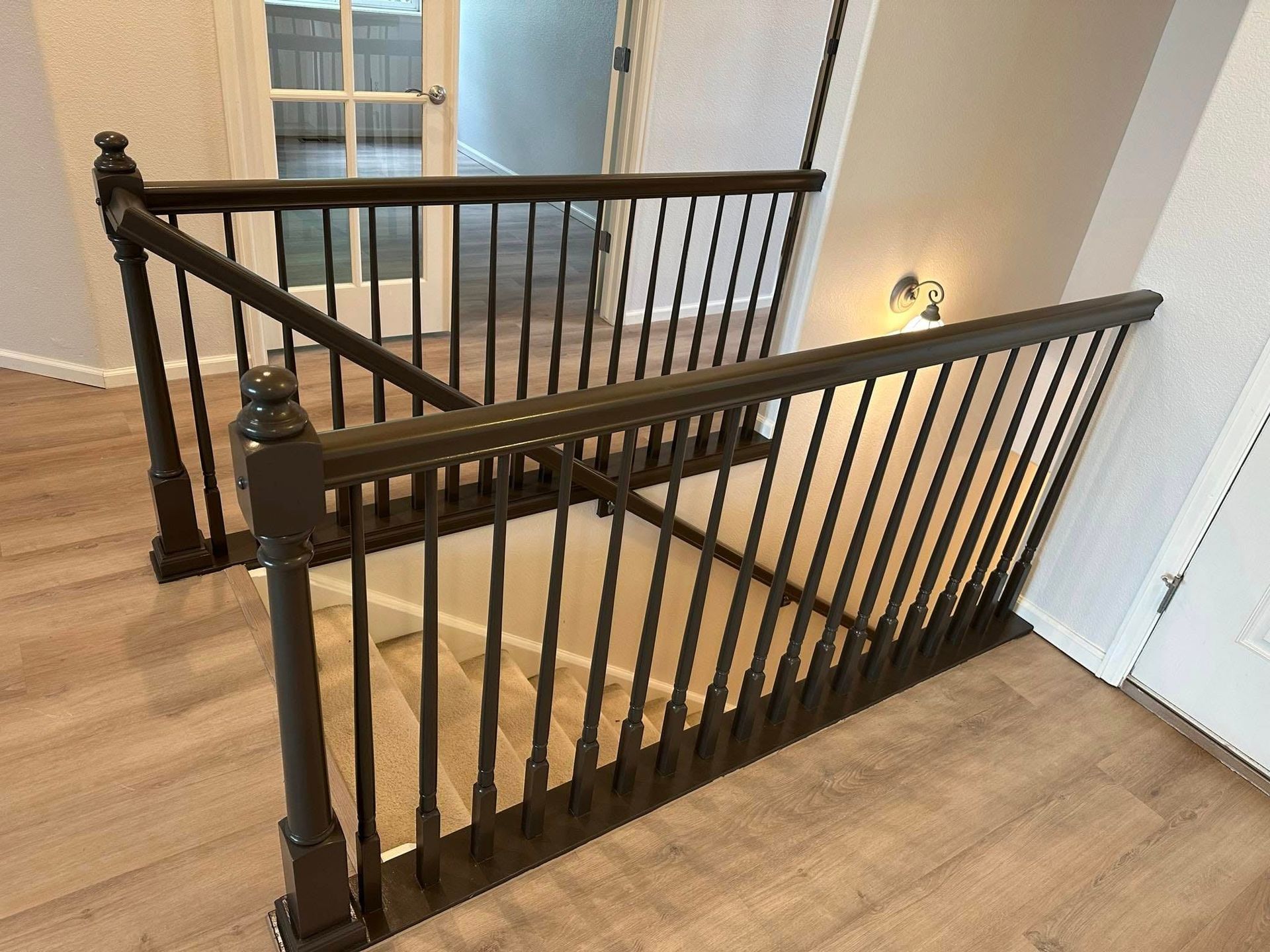 A wooden staircase with a black railing in a house.
