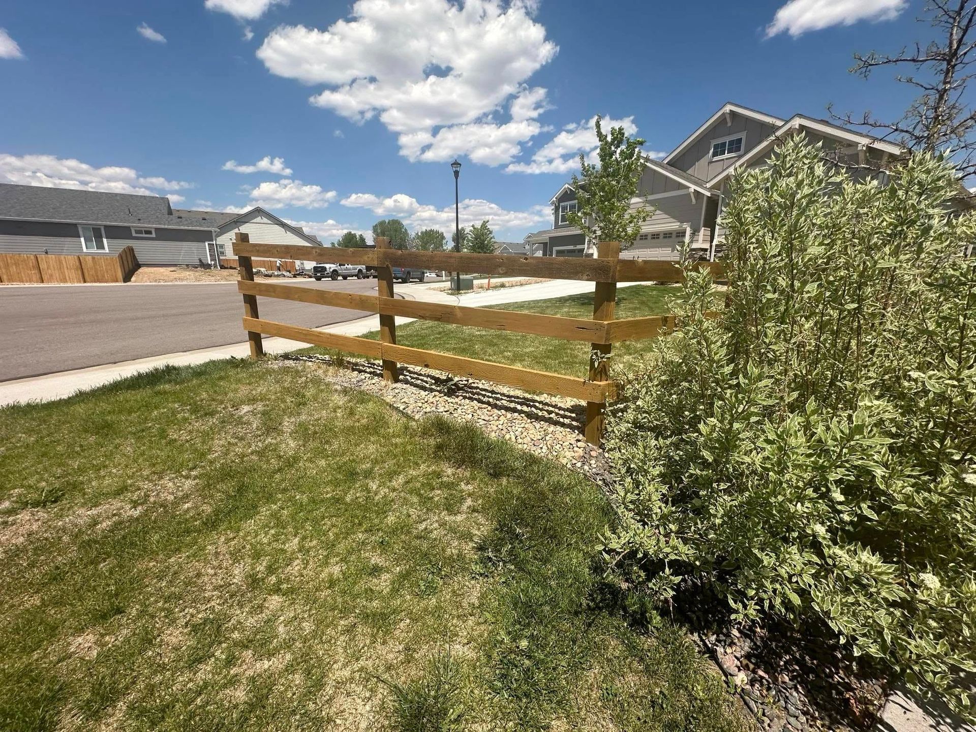 A wooden fence surrounds a lush green yard in a residential neighborhood.