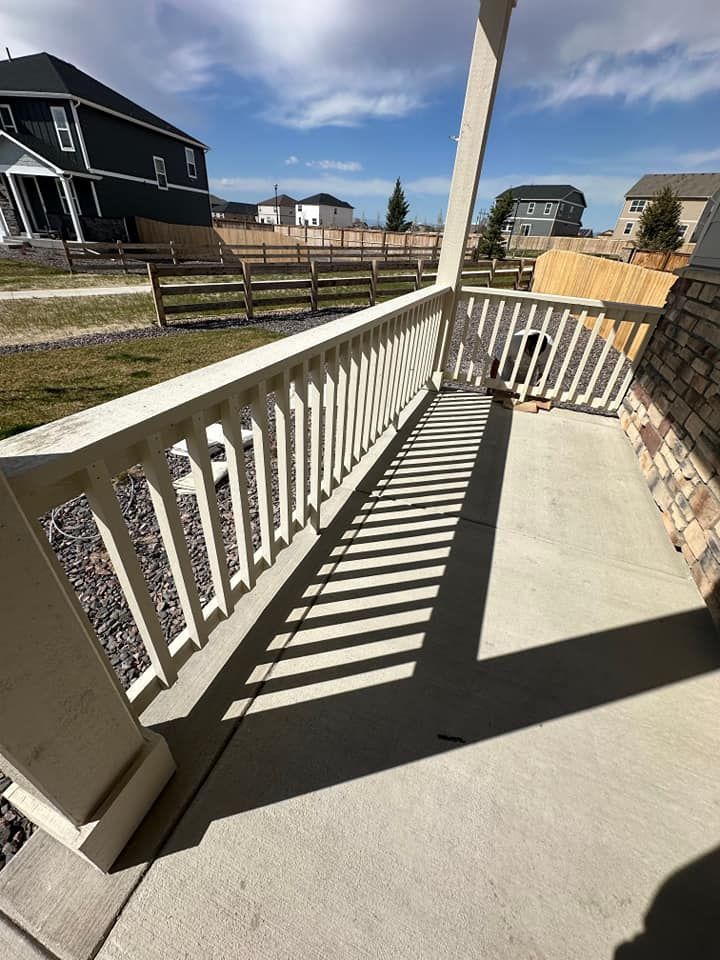 A white railing on a porch with a fence in the background.
