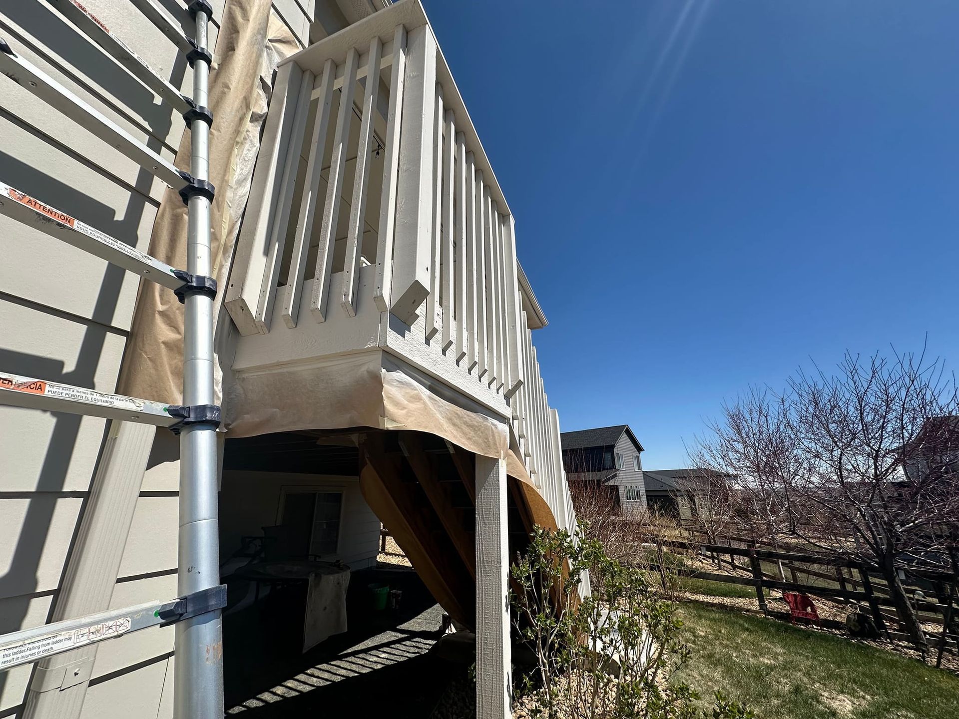 A house with a deck and stairs is being painted.