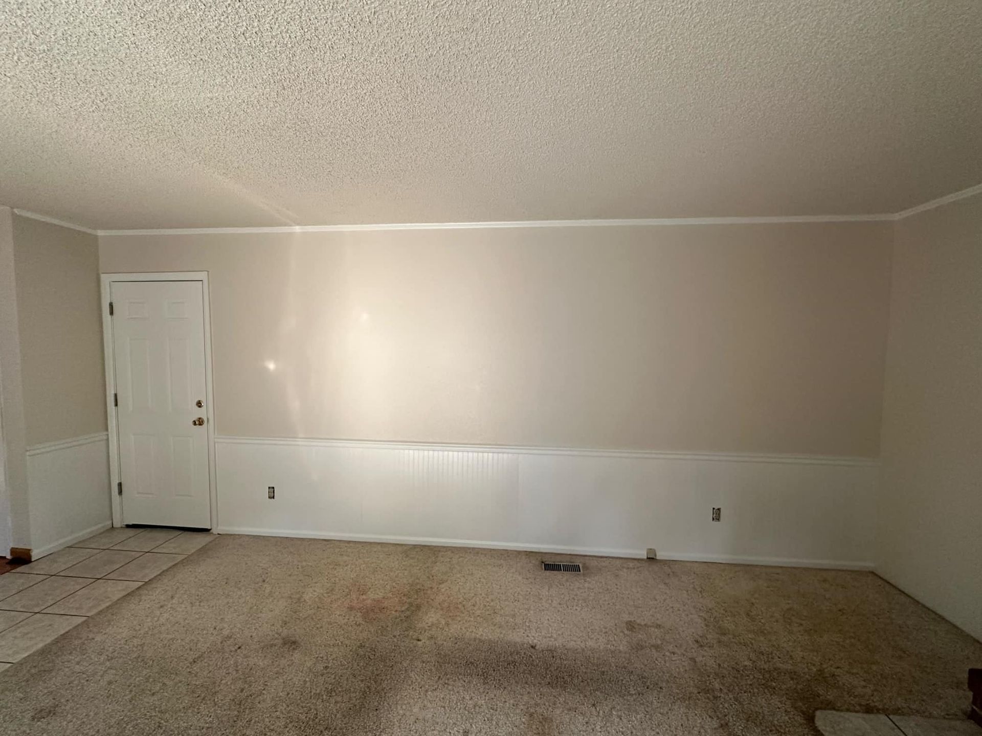 An empty living room with white walls and a door.