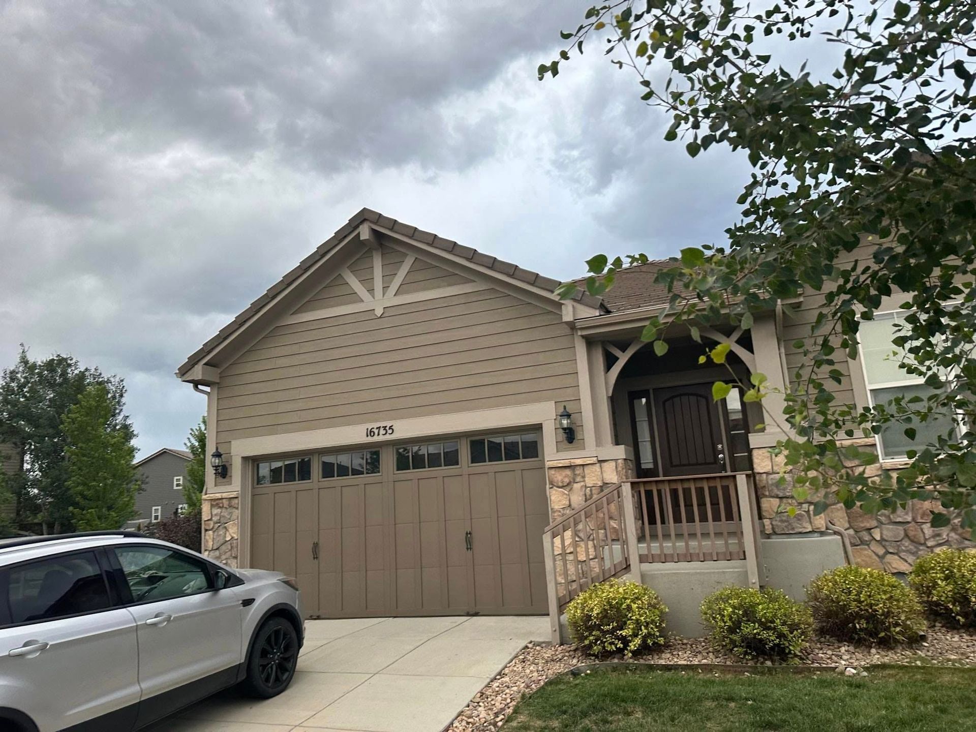 A car is parked in front of a house with a garage door.