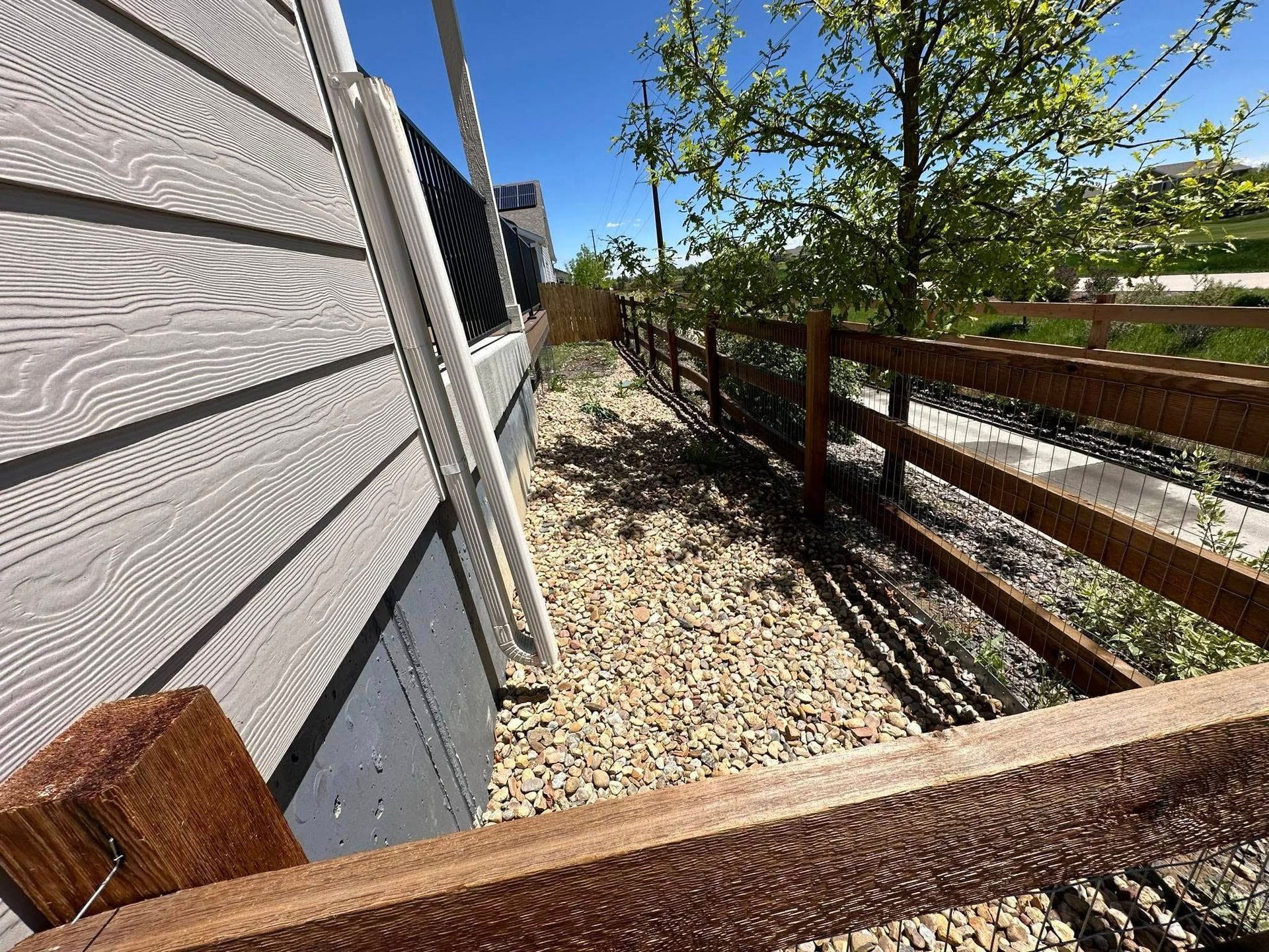 A wooden fence surrounds a yard next to a house.