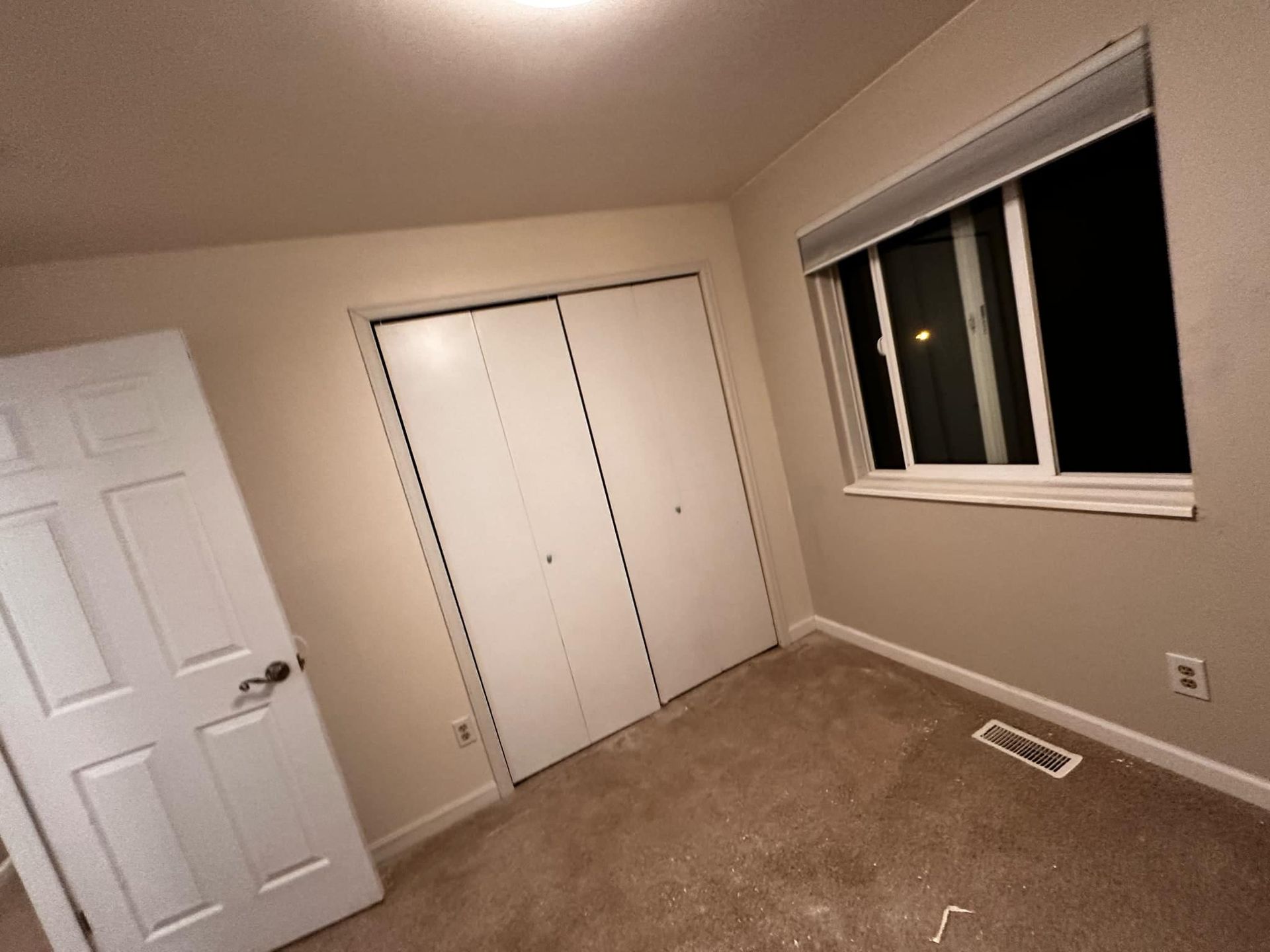 An empty bedroom with a window and closets