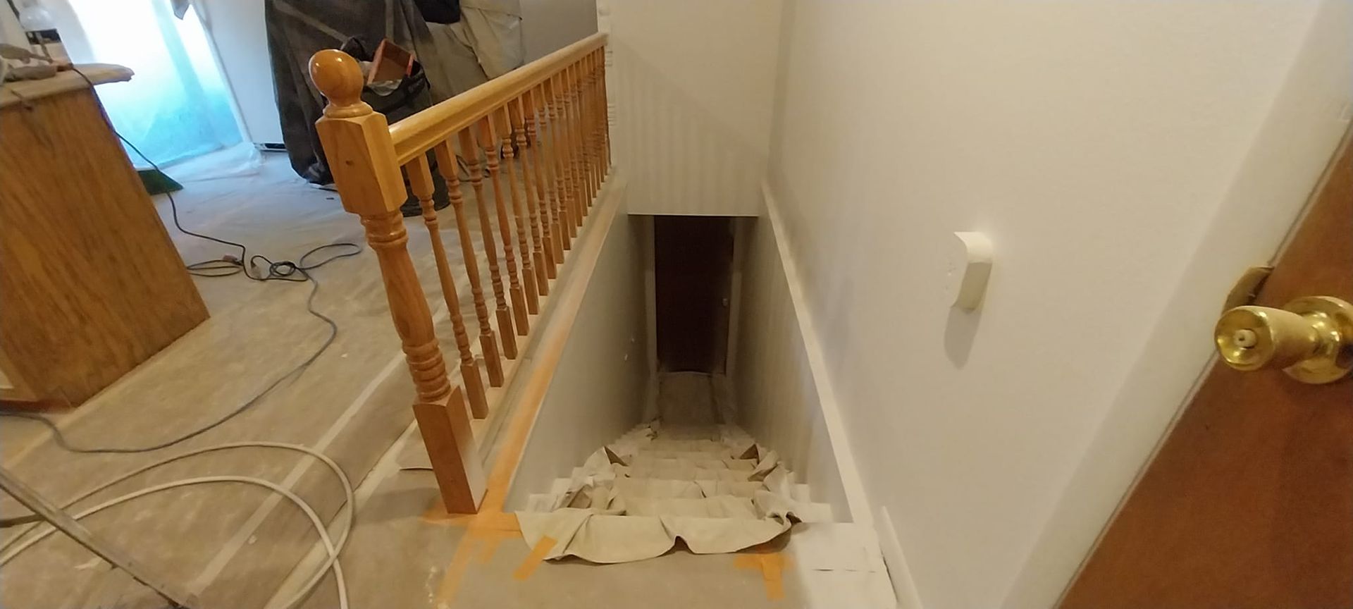 A staircase leading to a basement with a wooden railing and a door.