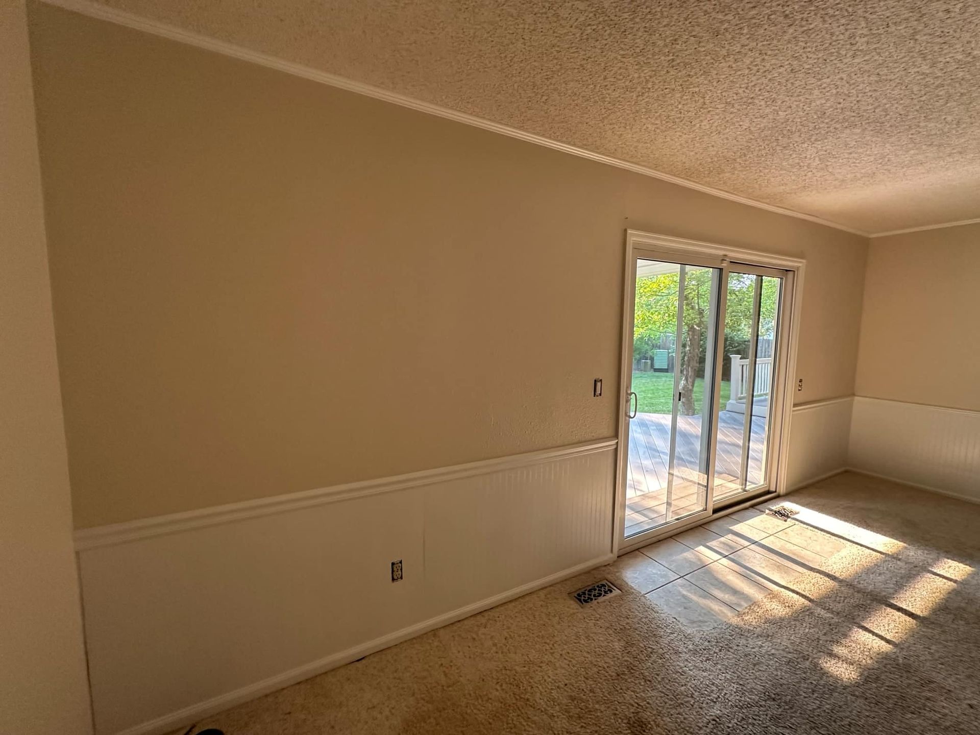 An empty living room with a sliding glass door.