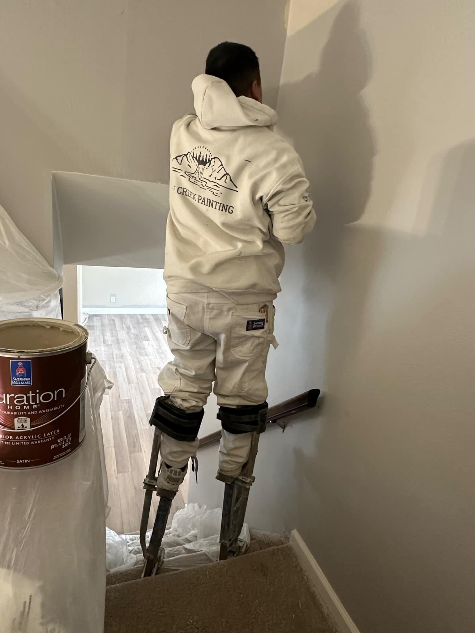 A man is standing on a ladder painting a wall.