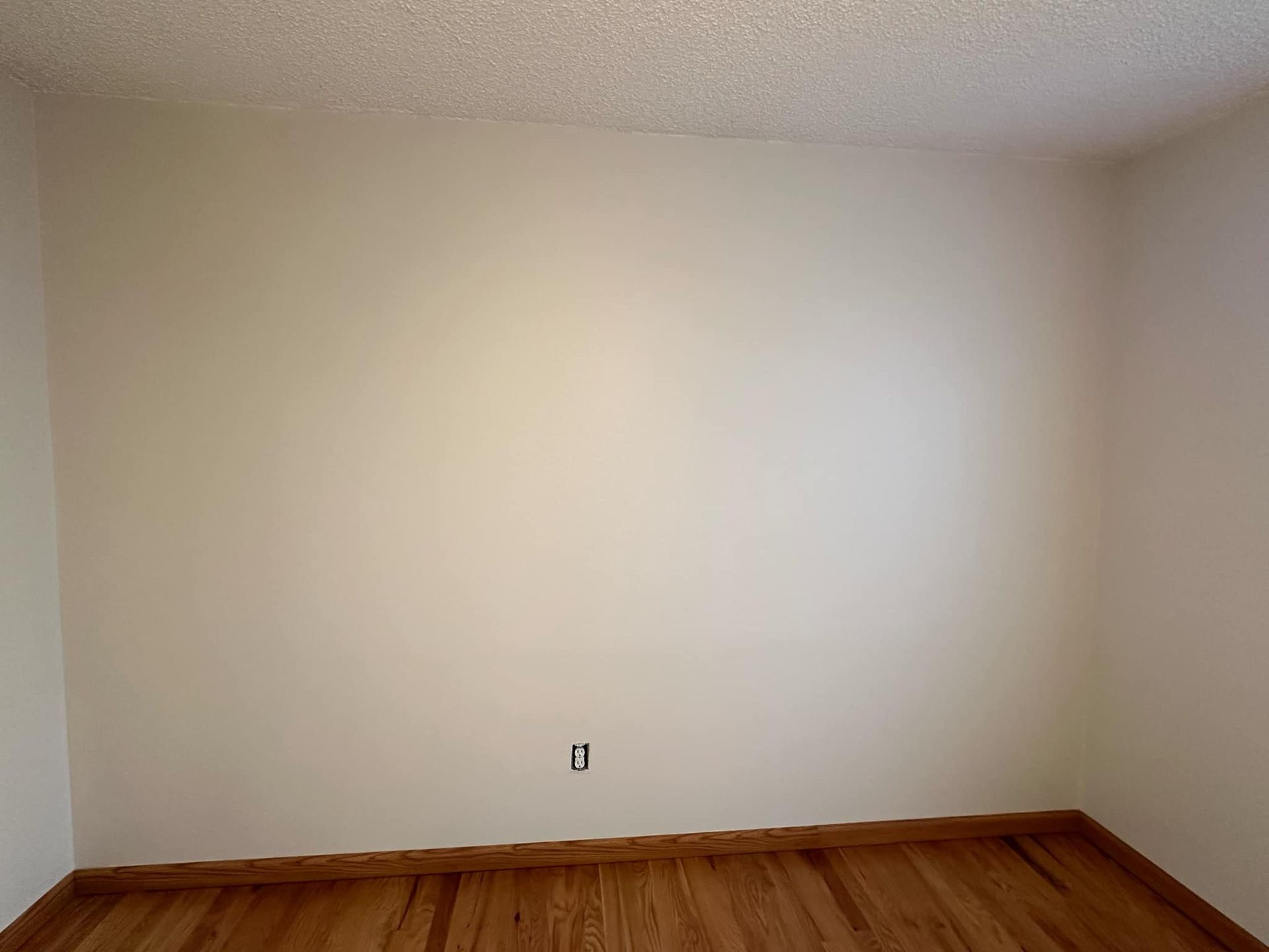 An empty room with hardwood floors and white walls.