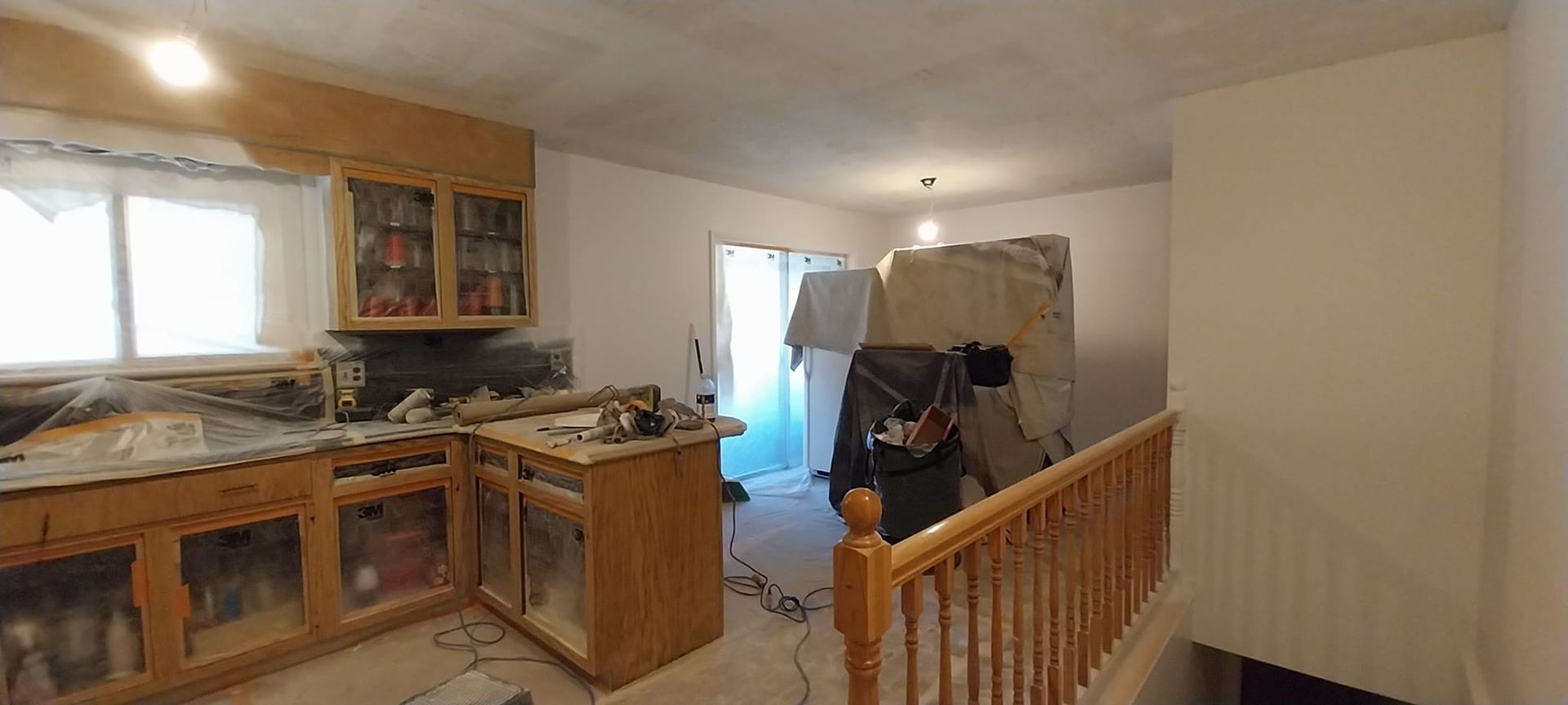 A kitchen with wooden cabinets and a wooden railing is being remodeled.