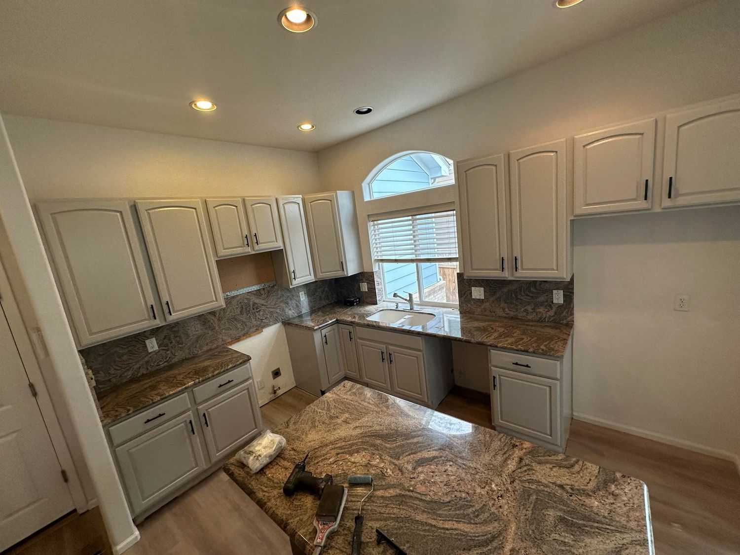 A kitchen with white cabinets and granite counter tops is being remodeled.