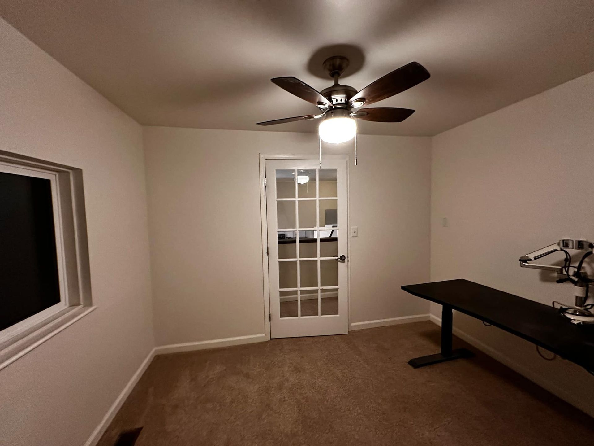 An empty room with a ceiling fan and a desk