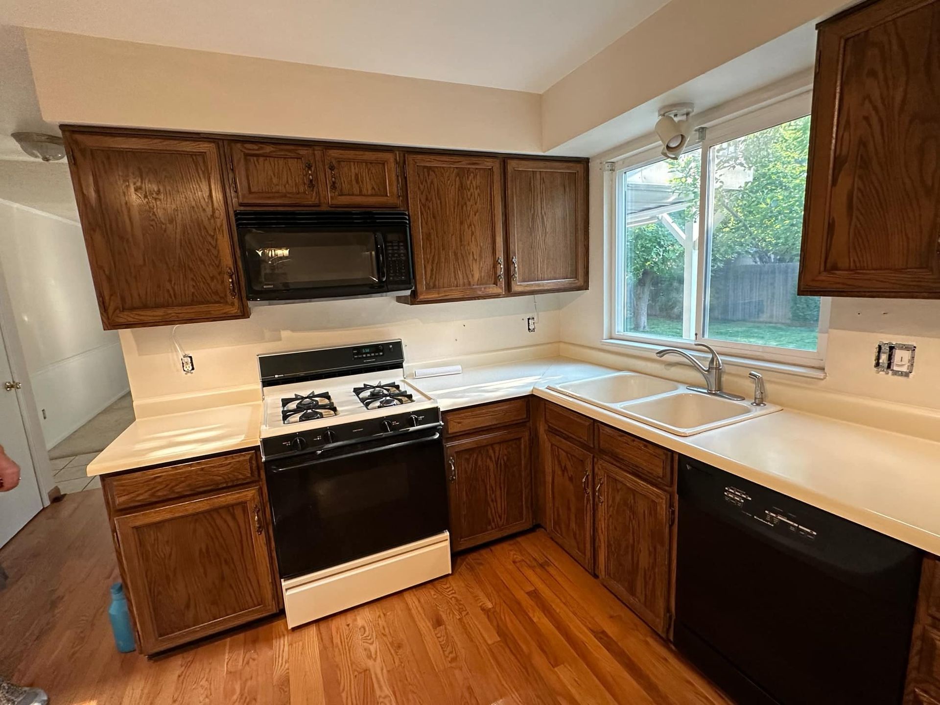 A kitchen with wooden cabinets , a stove , a microwave , and a sink.