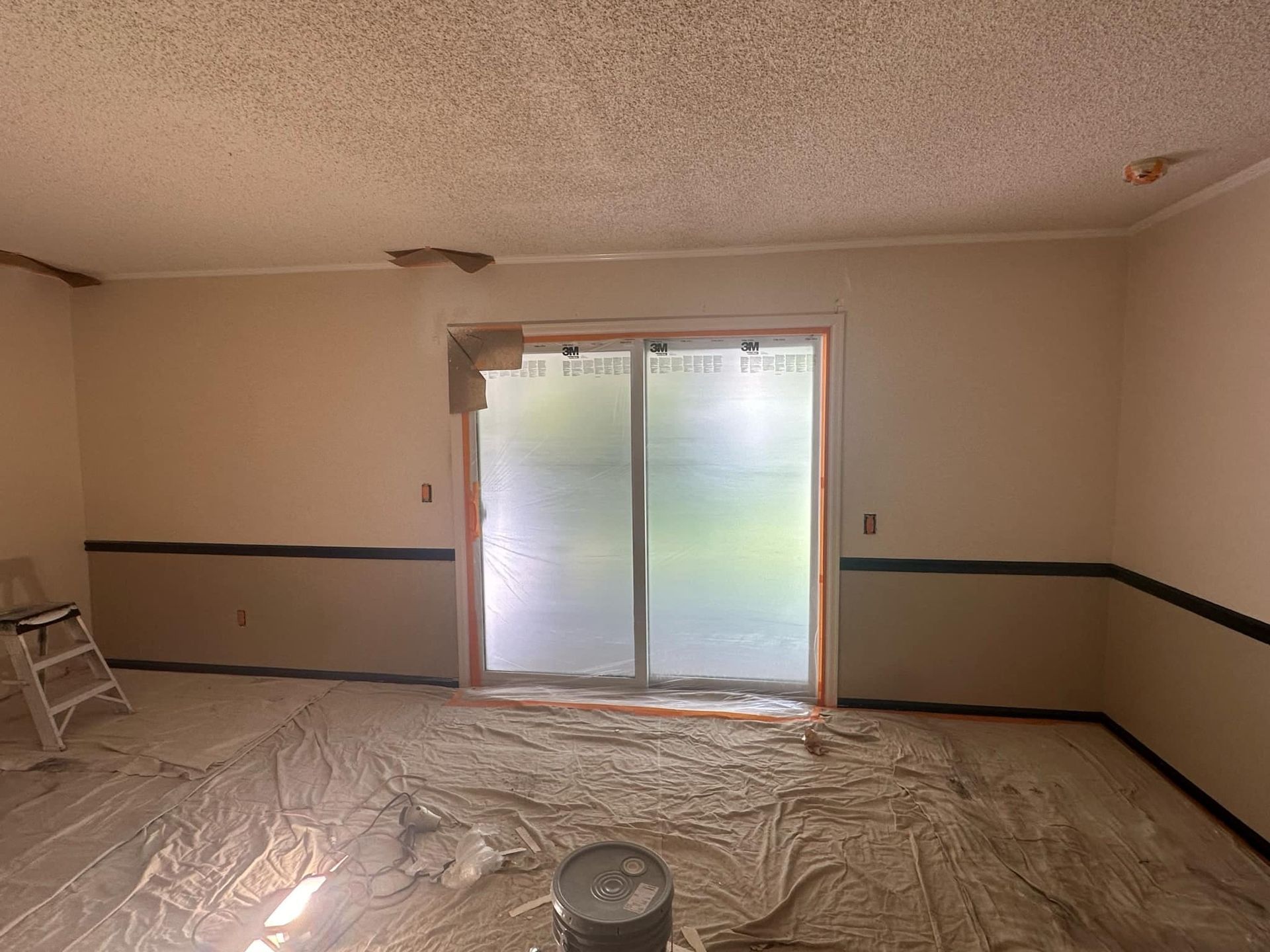 A room with a sliding glass door is being painted.