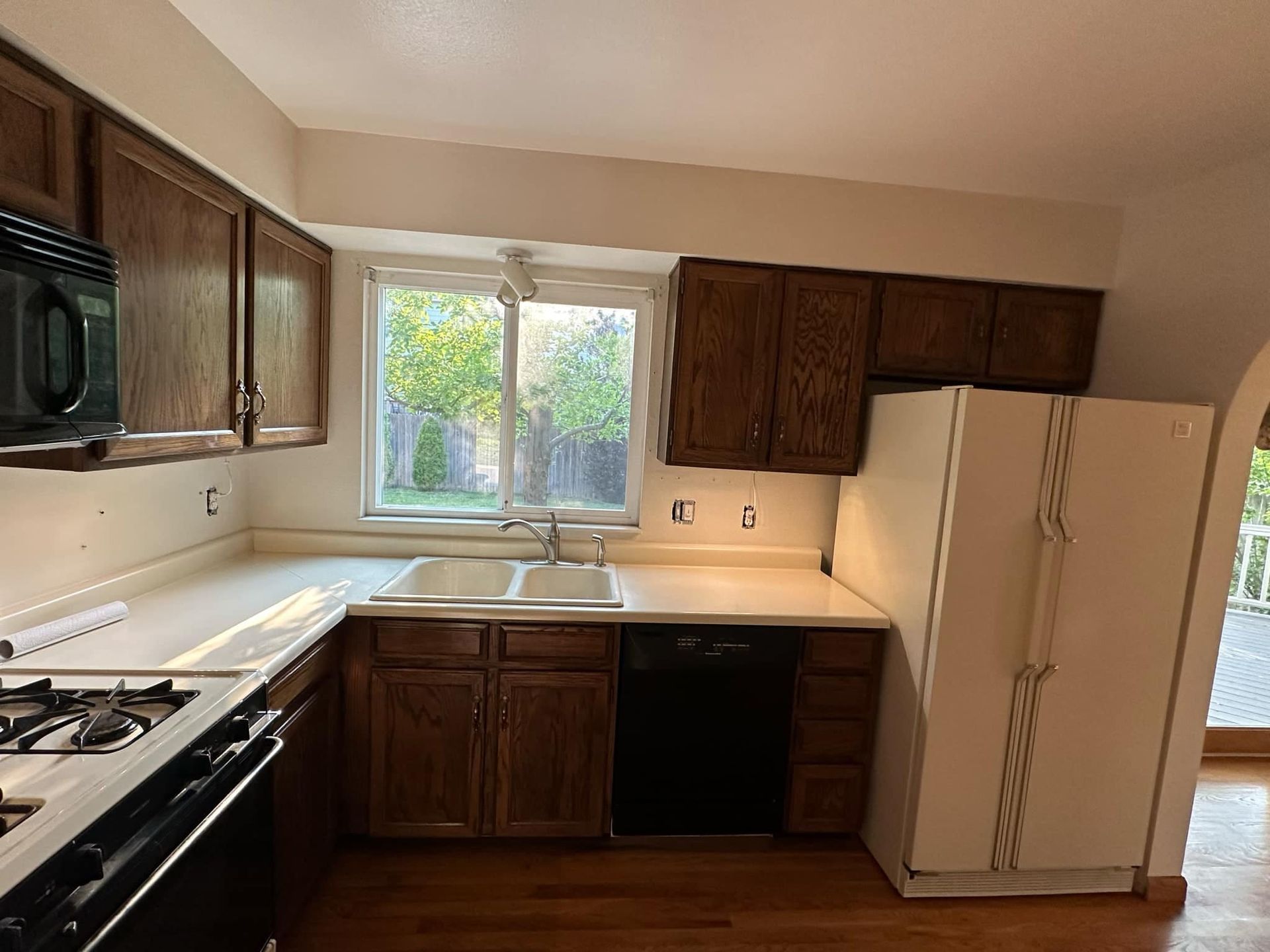 A kitchen with a stove , sink , refrigerator and microwave.