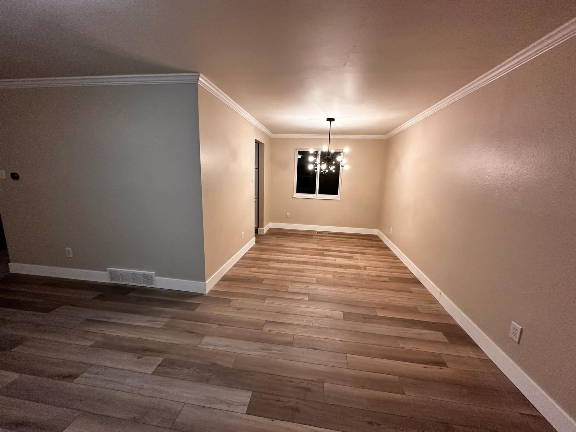 An empty living room with hardwood floors and a window.