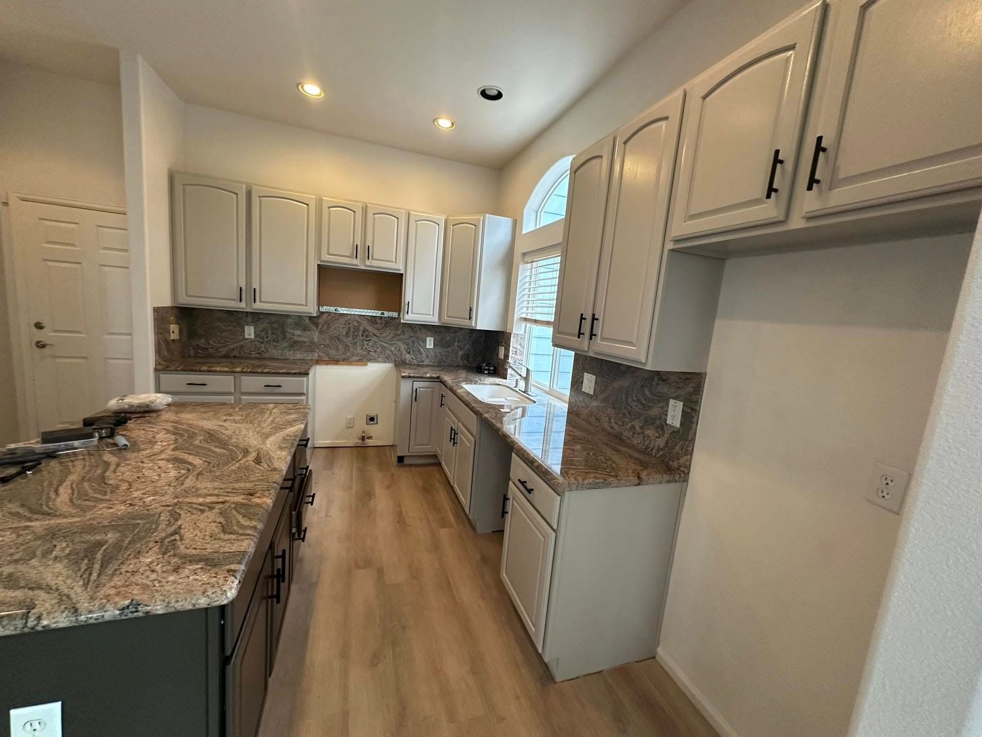 A kitchen with white cabinets and granite counter tops.