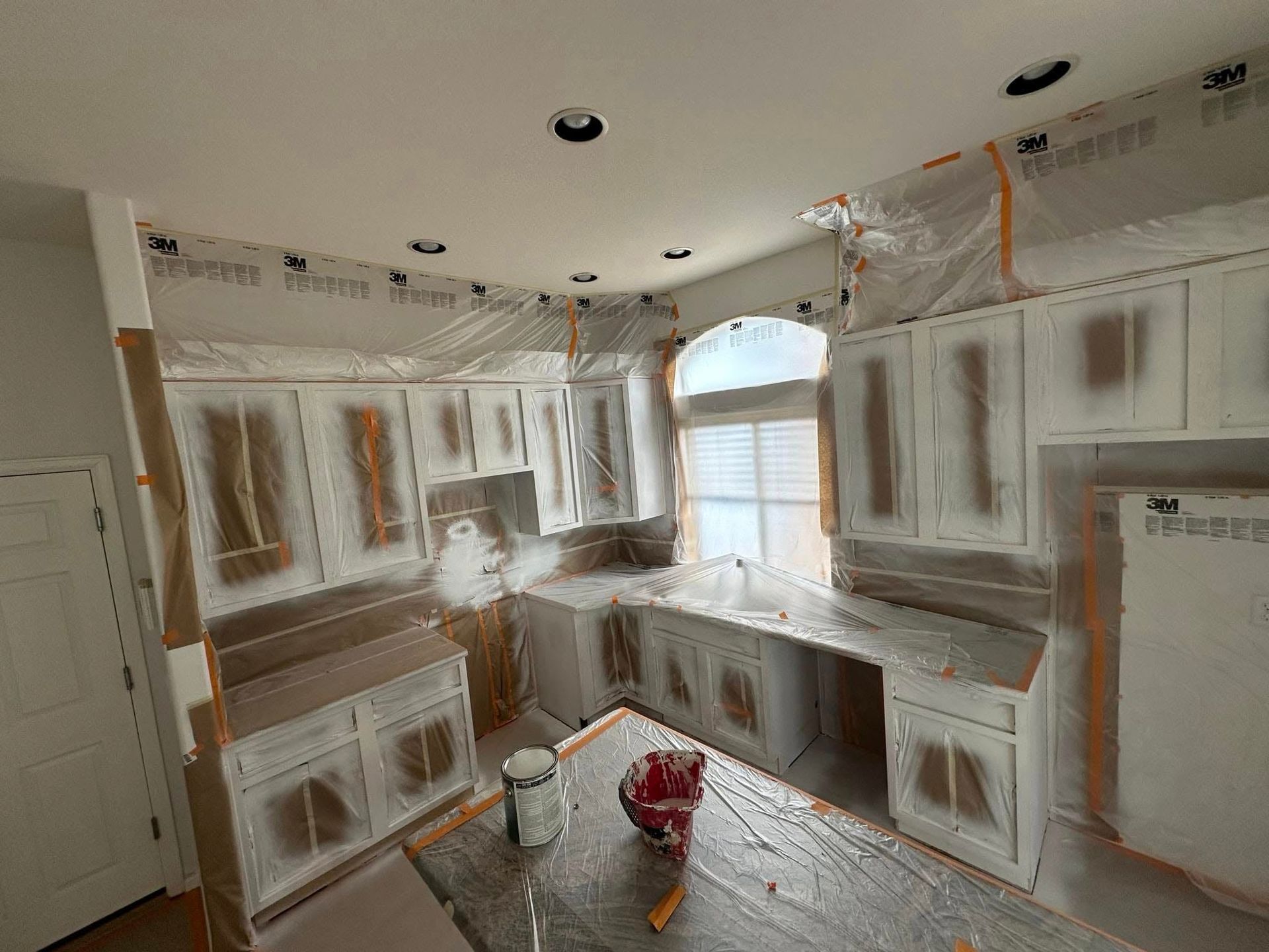 A kitchen is being painted and covered in plastic.
