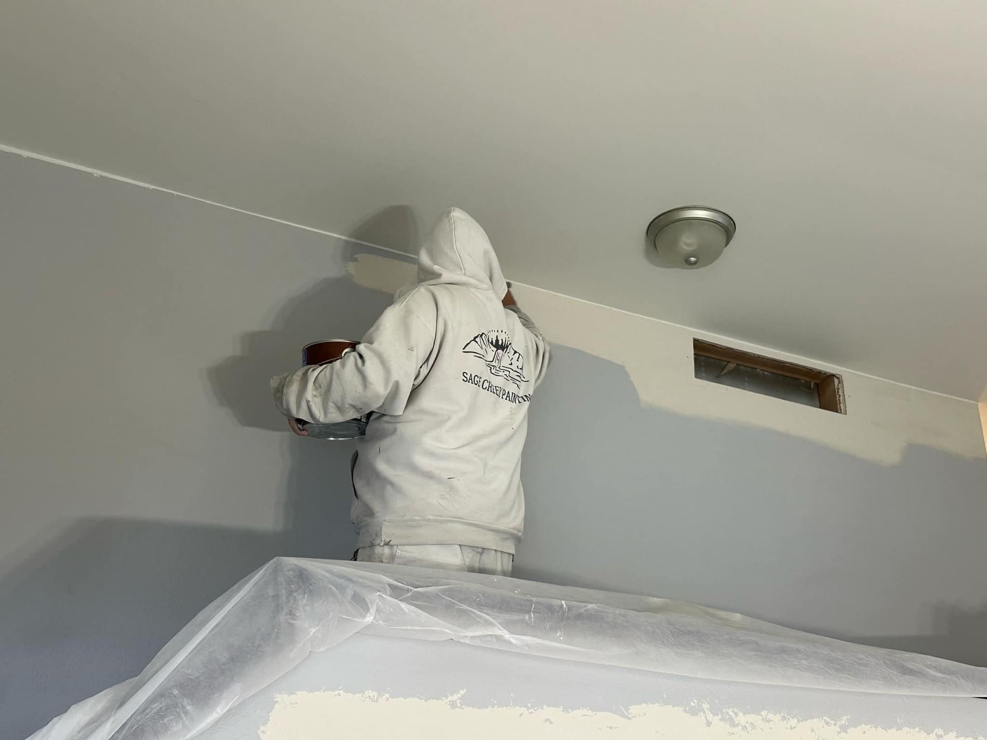 A man in a white jacket is standing on a table in a room.