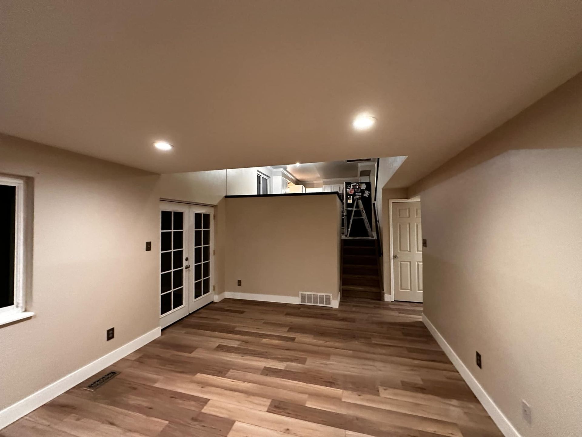 An empty basement with hardwood floors and a staircase.
