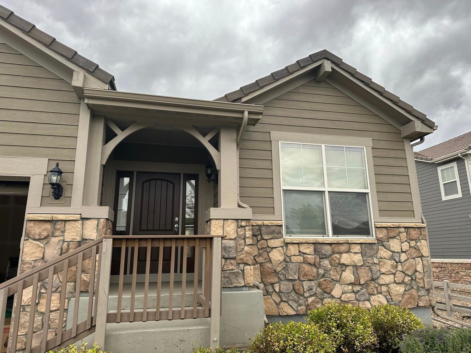 The front of a house with a stone wall and a porch.