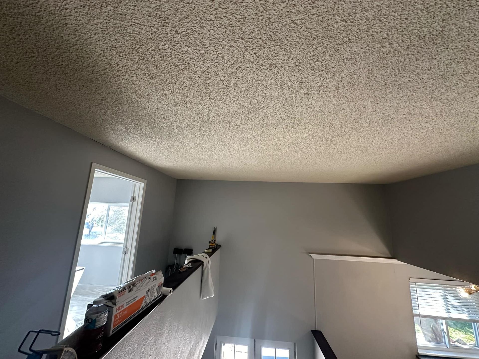 A room with a staircase and a ceiling with a lot of dust on it.