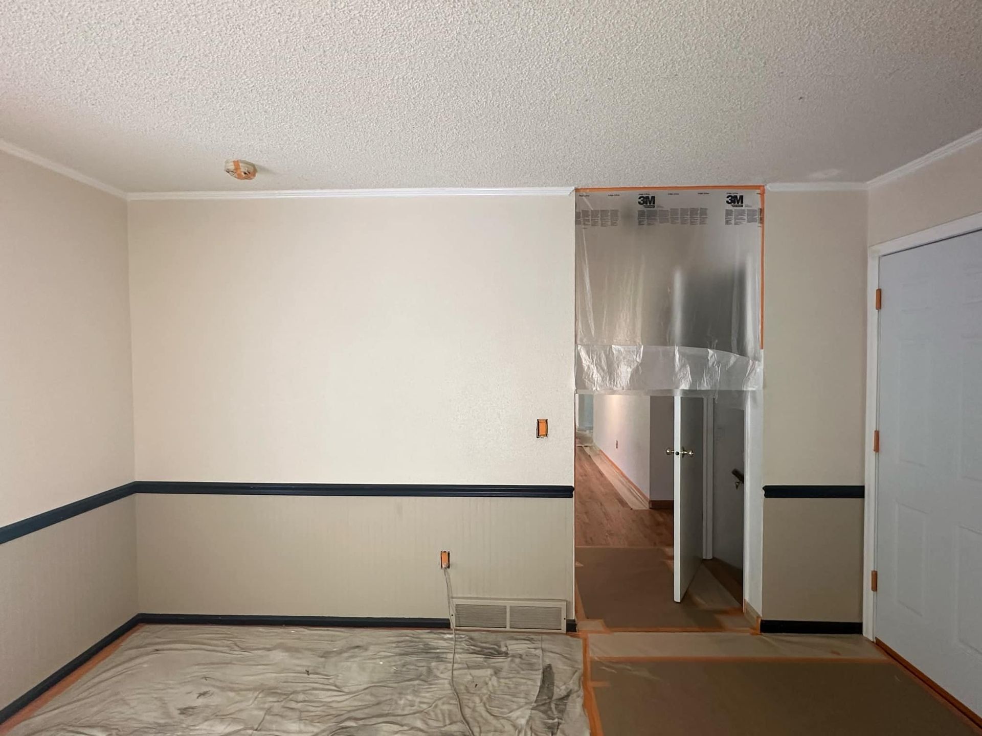 An empty room with white walls and black trim is being painted.