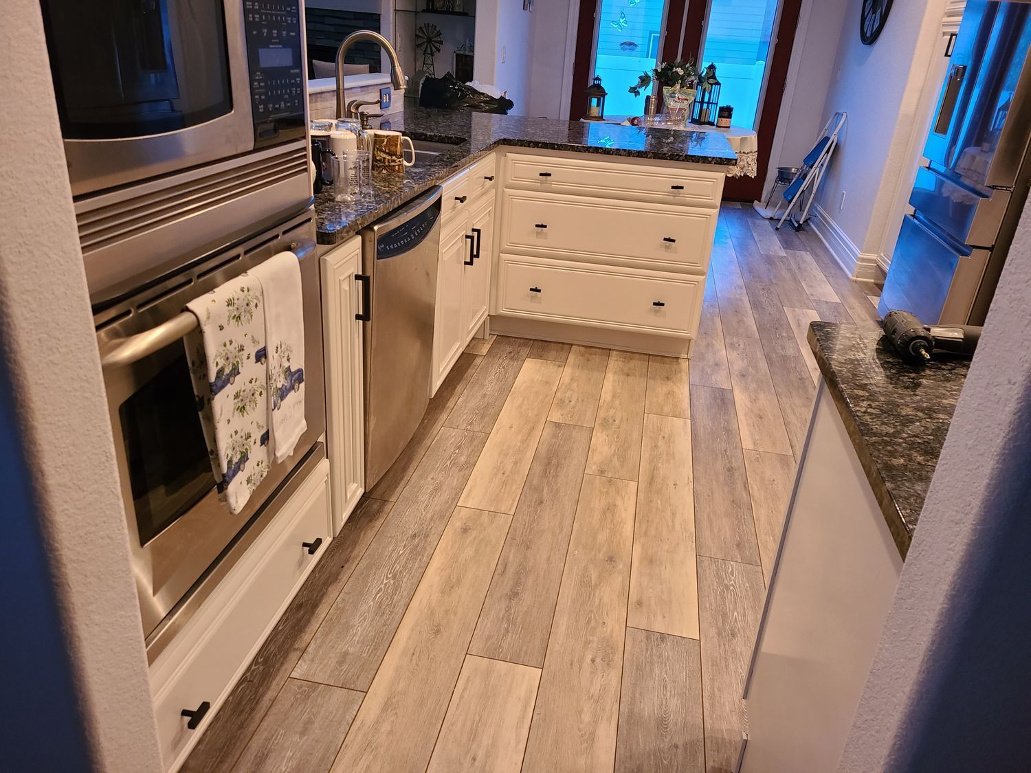 A kitchen with stainless steel appliances and wooden floors.